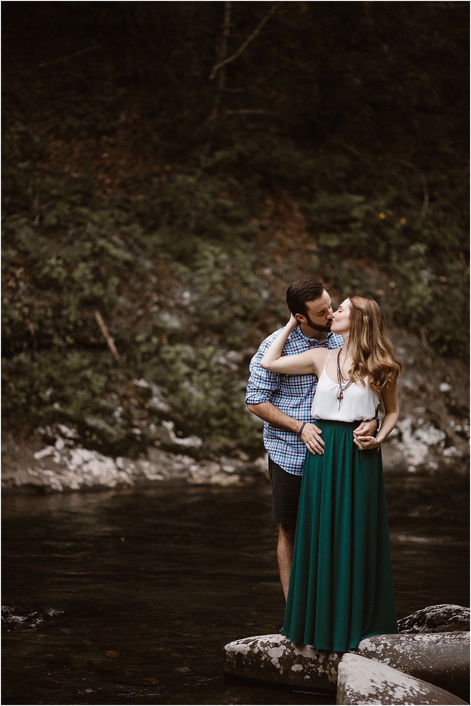 girl in white and green dress kissing man in plaid shirt on river
