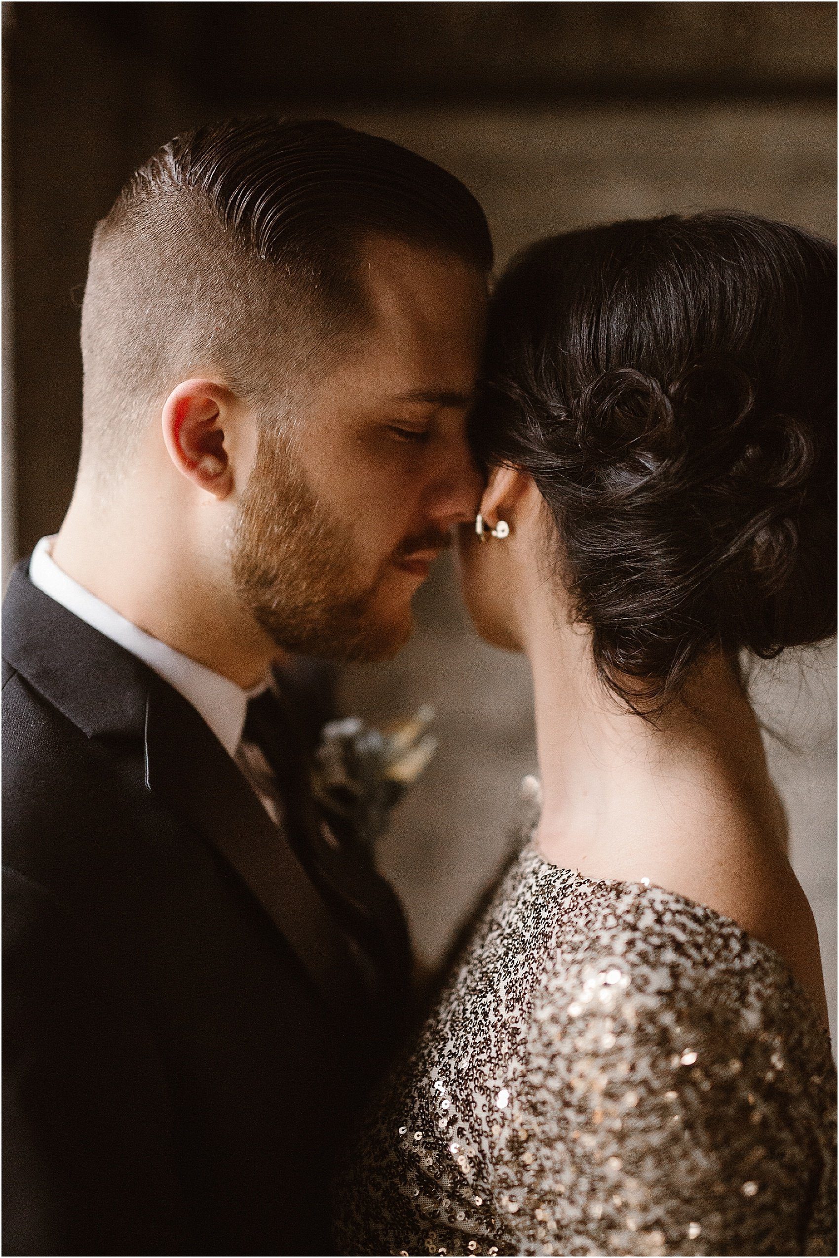 man whispers into ear of woman wearing gold dress 
