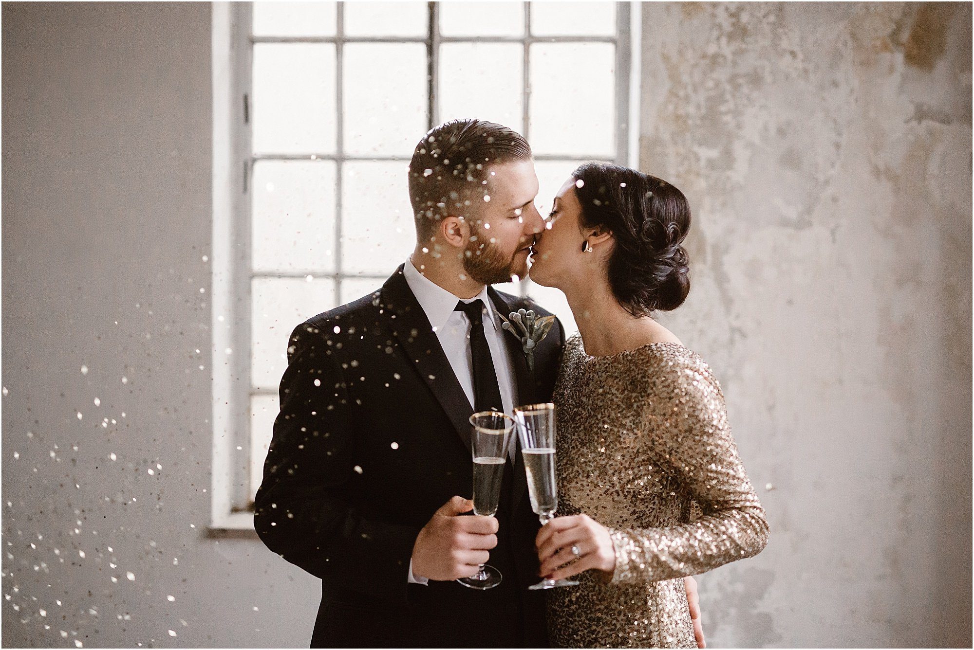 man and woman kiss while confetti rains down from ceiling