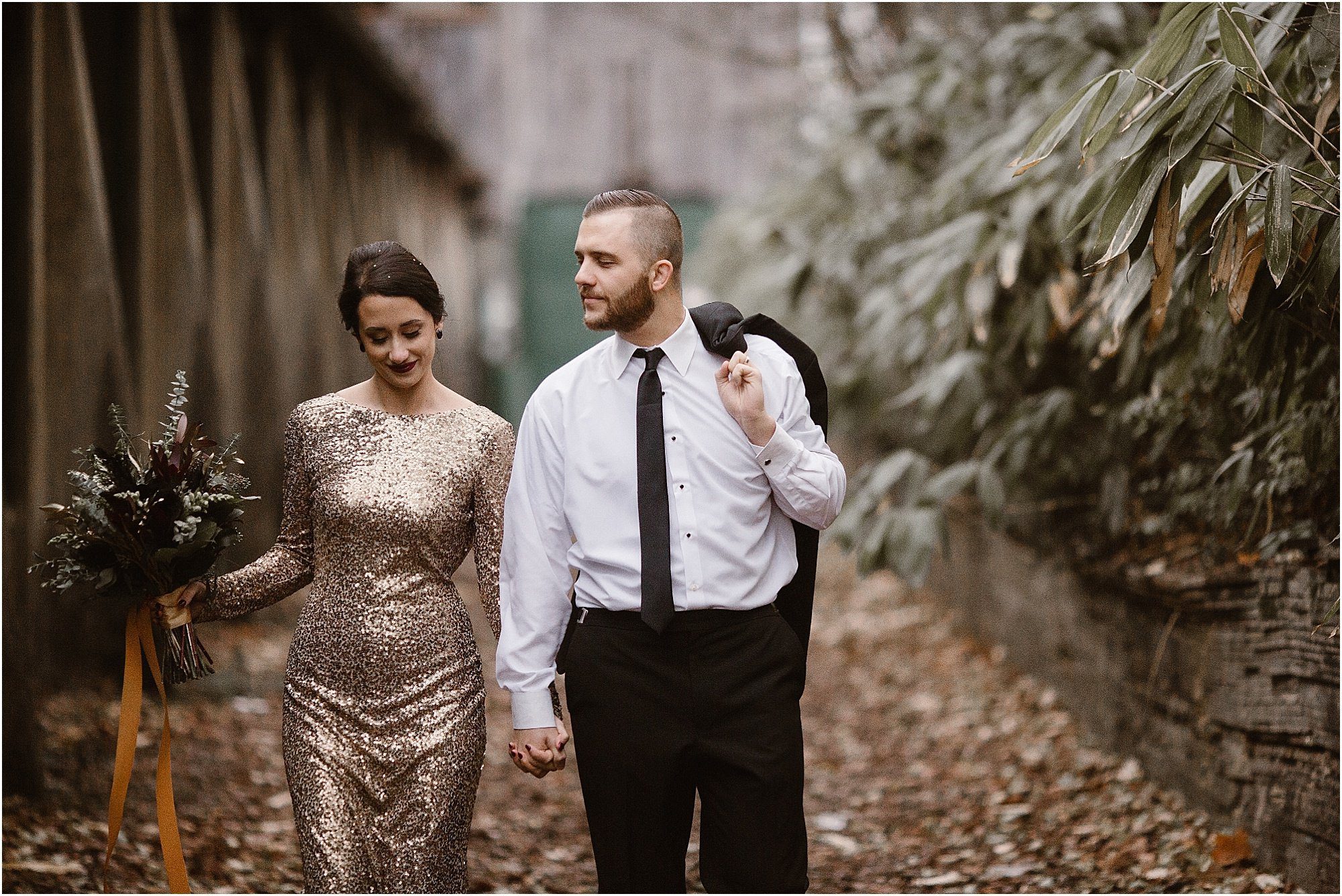 man and woman walk and hold hands at gold and black wedding inspiration at historic marble factory