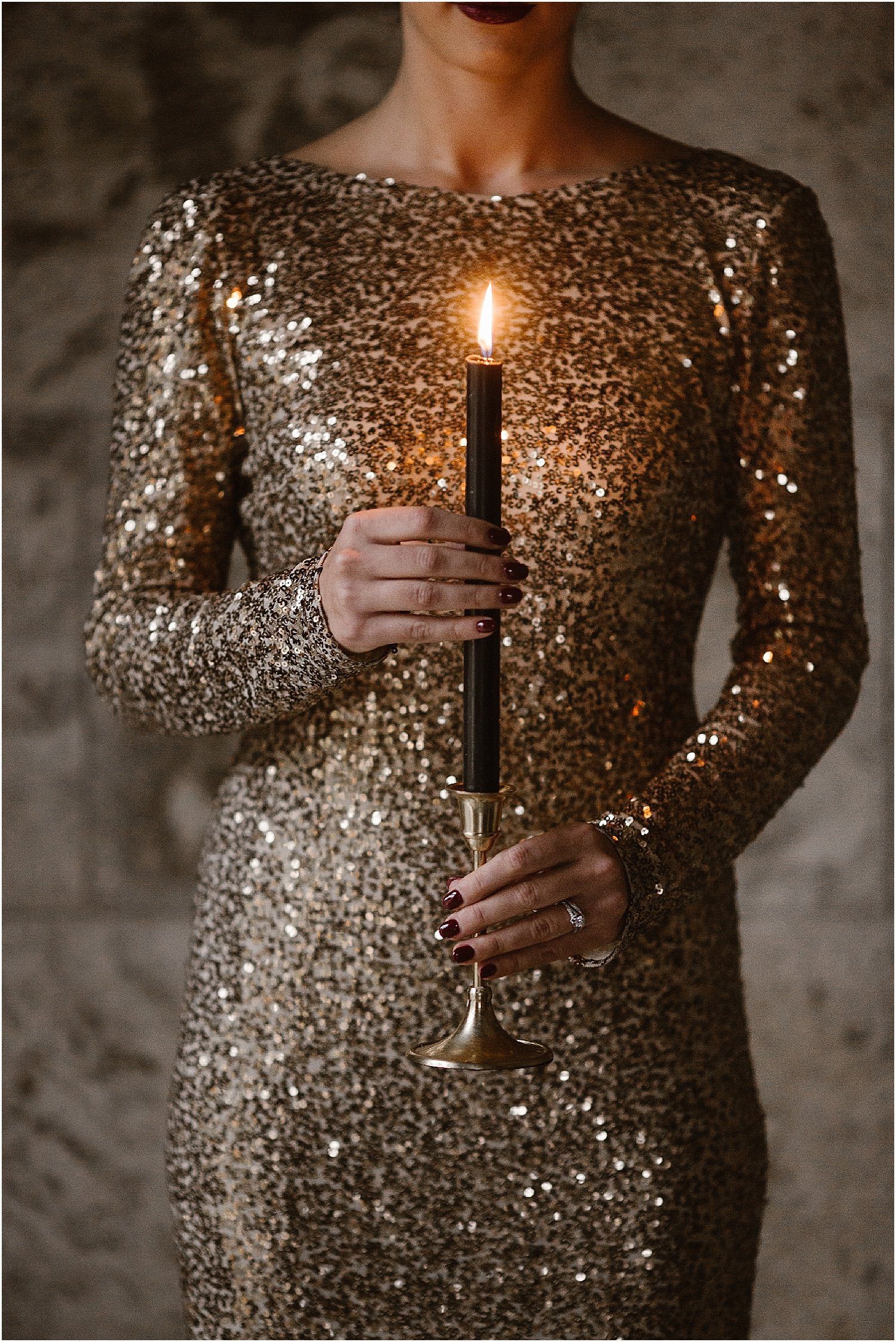 woman holding black candle stick while wearing sequined gold dress 