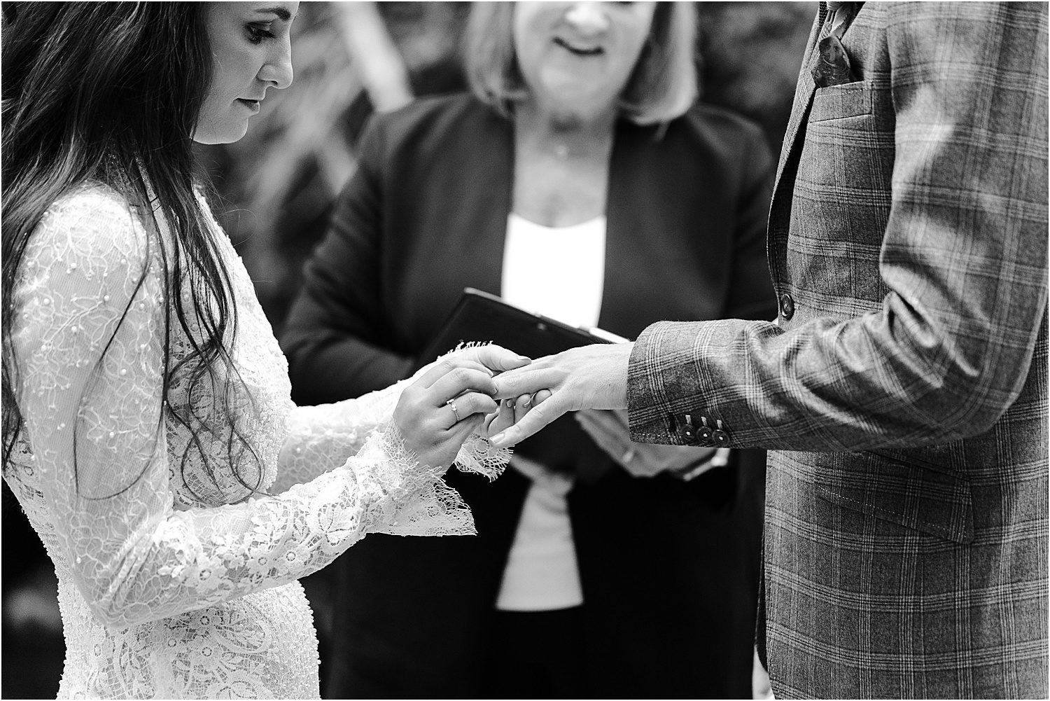 black and white photo of bride putting ring on groom's hand