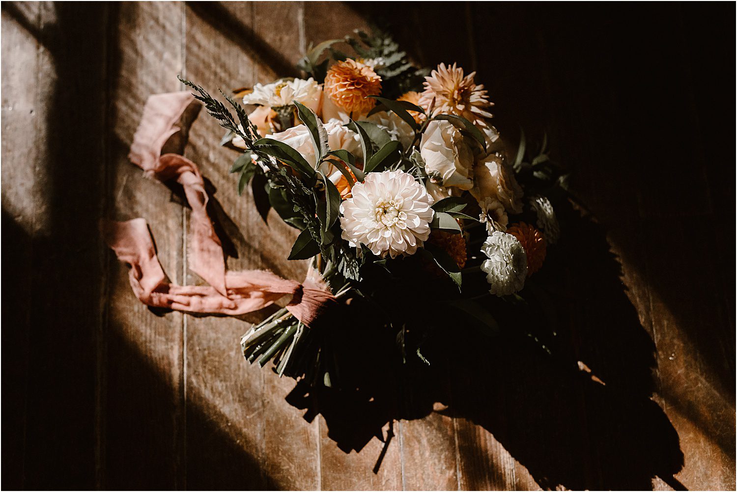 organic fall wedding dress laying on wooden floor in window light
