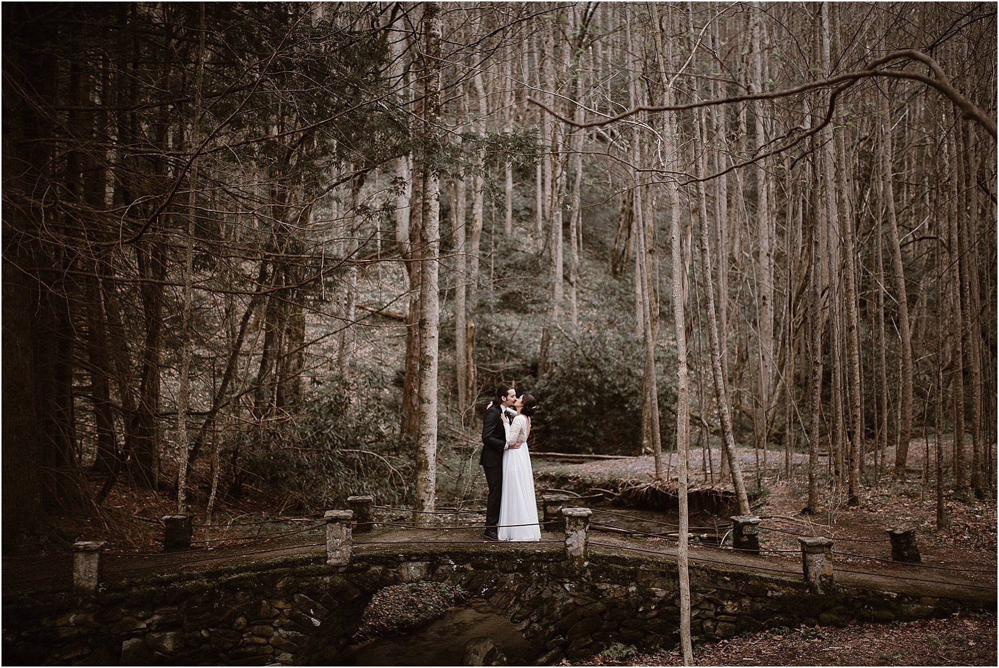 Bride and groom on bridge in woods at Elopement