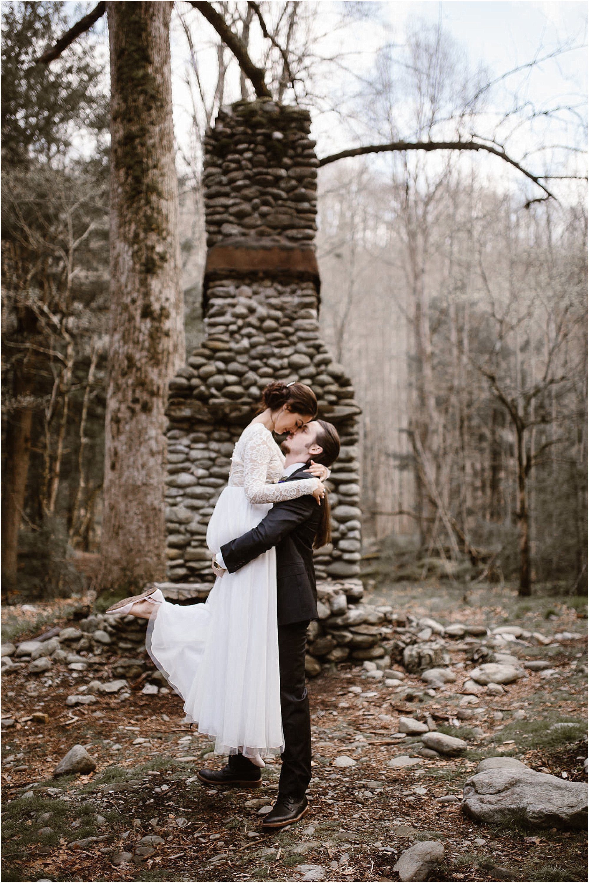 Groom lifting bride in front of chimney at Smokies