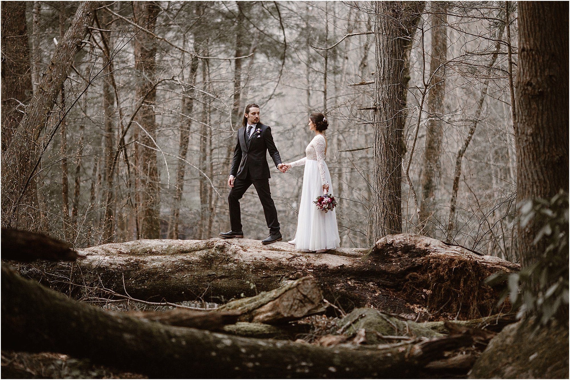 Bride and Groom walking across log at elopement in mountains