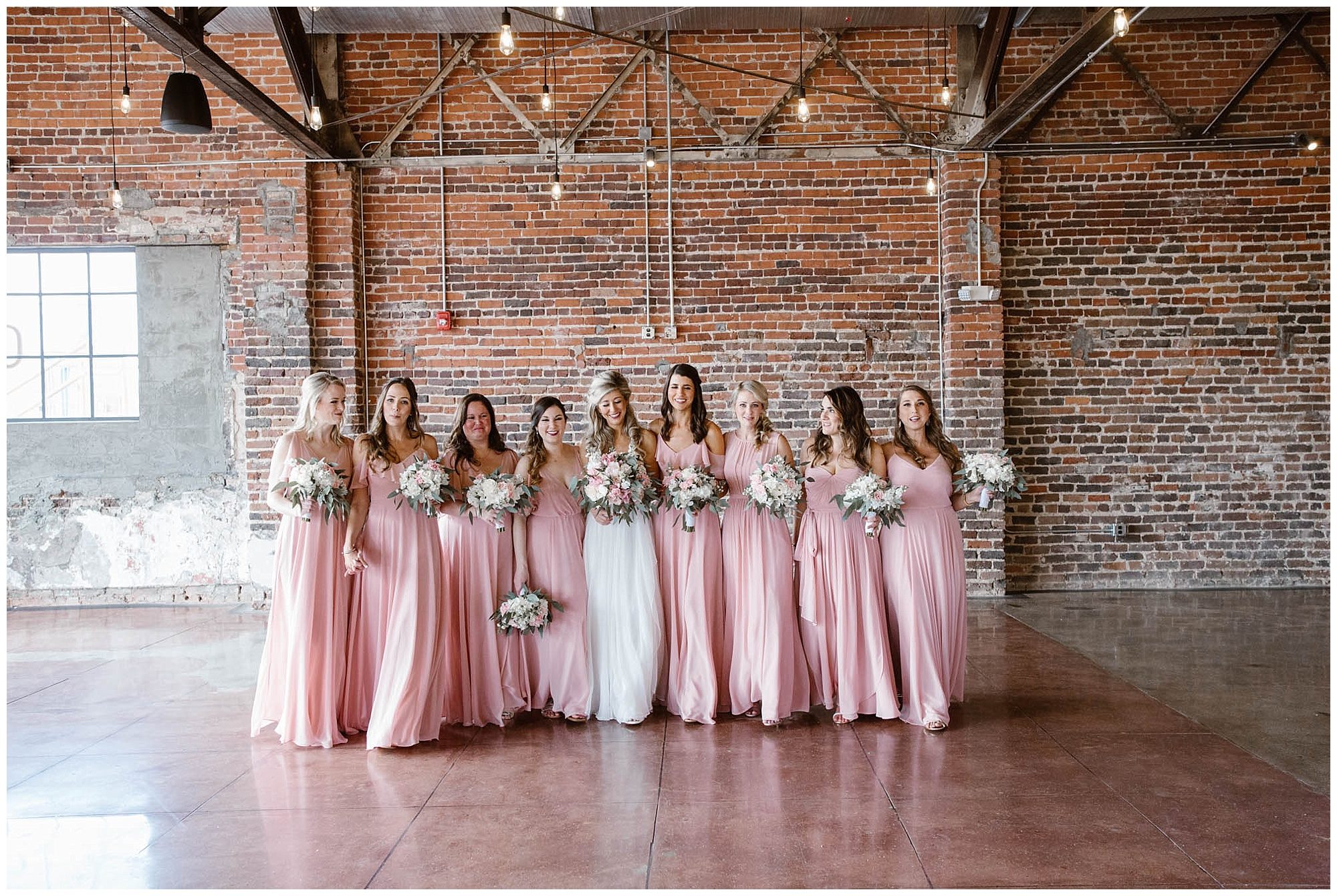 bride and bridesmaids walking in pink dresses with flowers from Lisa Foster