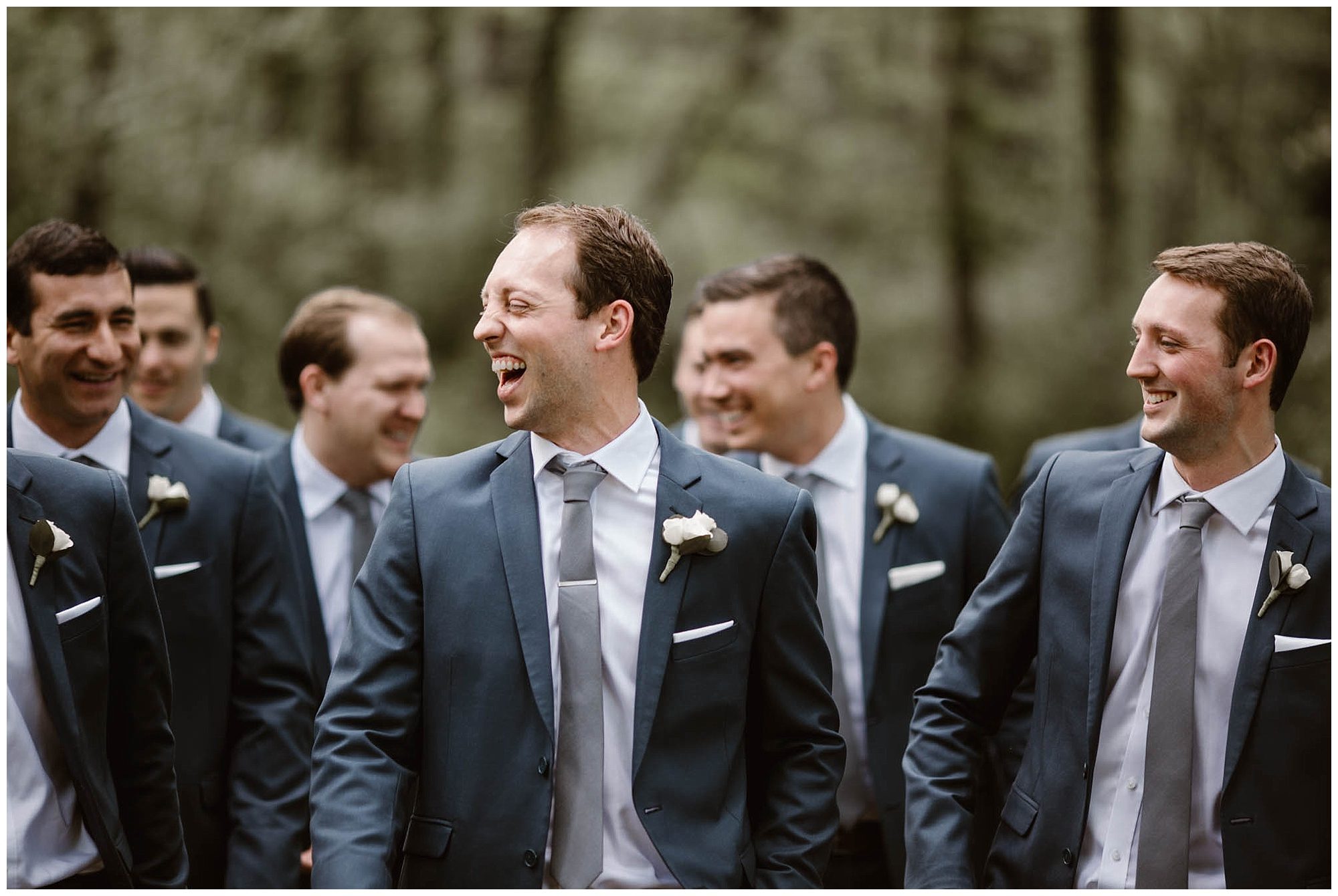 groom laughing with groomsmen in forest
