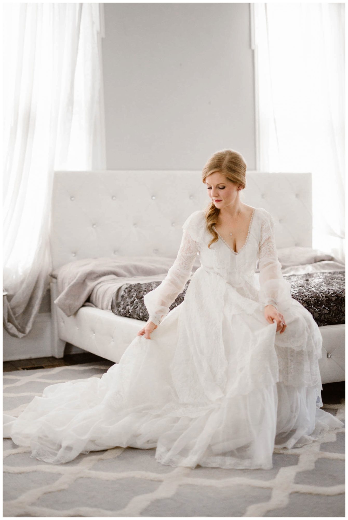 bride sitting on bed fluffing vintage wedding dress