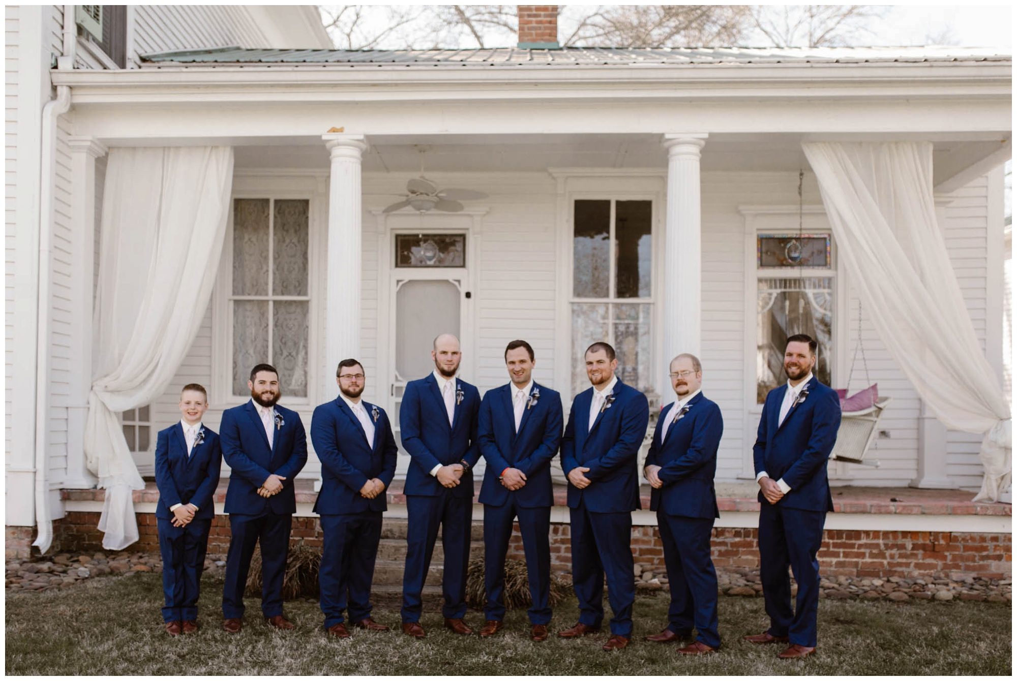 groom and groomsmen standing in front of white house