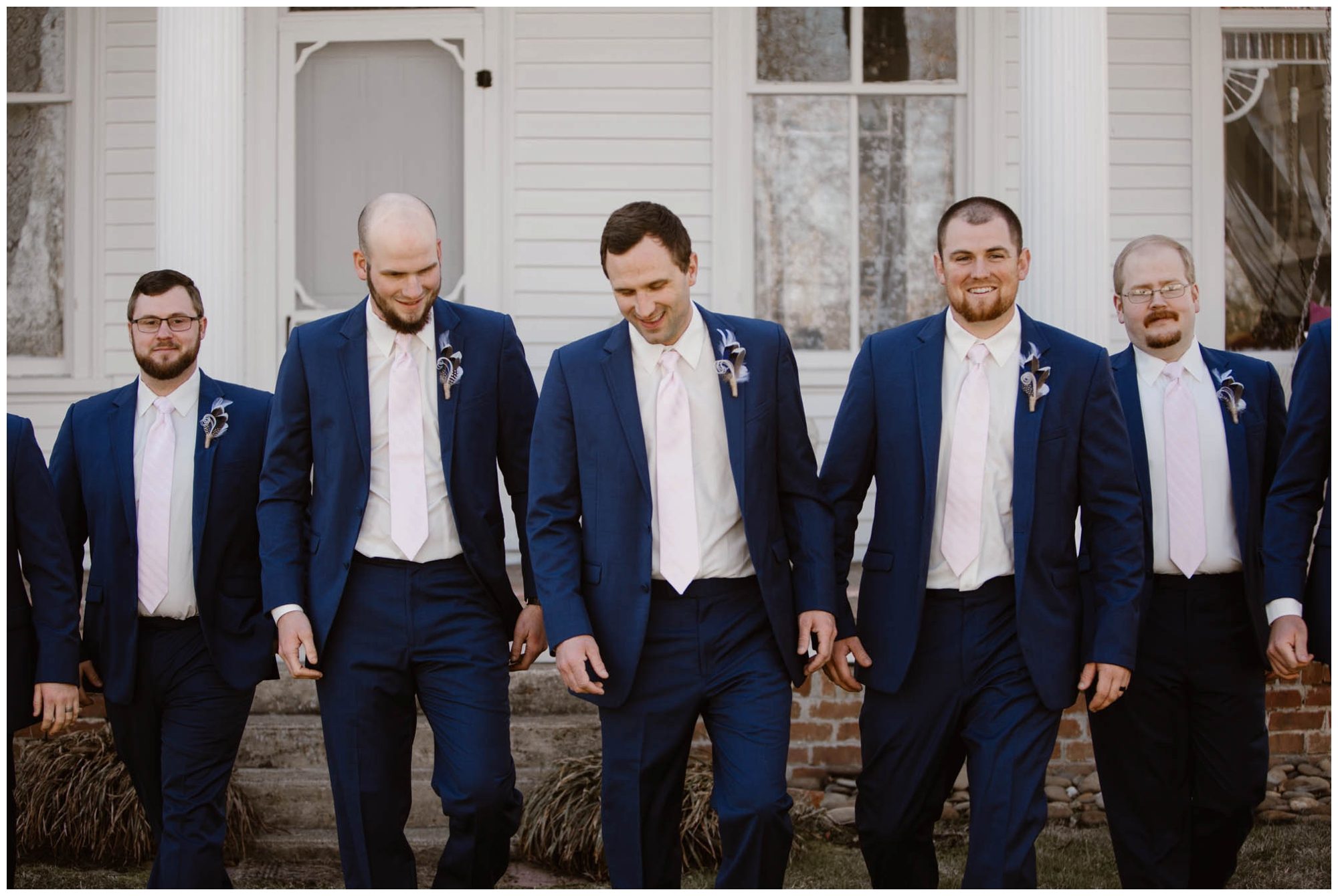 groom and groomsmen in blue suits walking outside of white house 