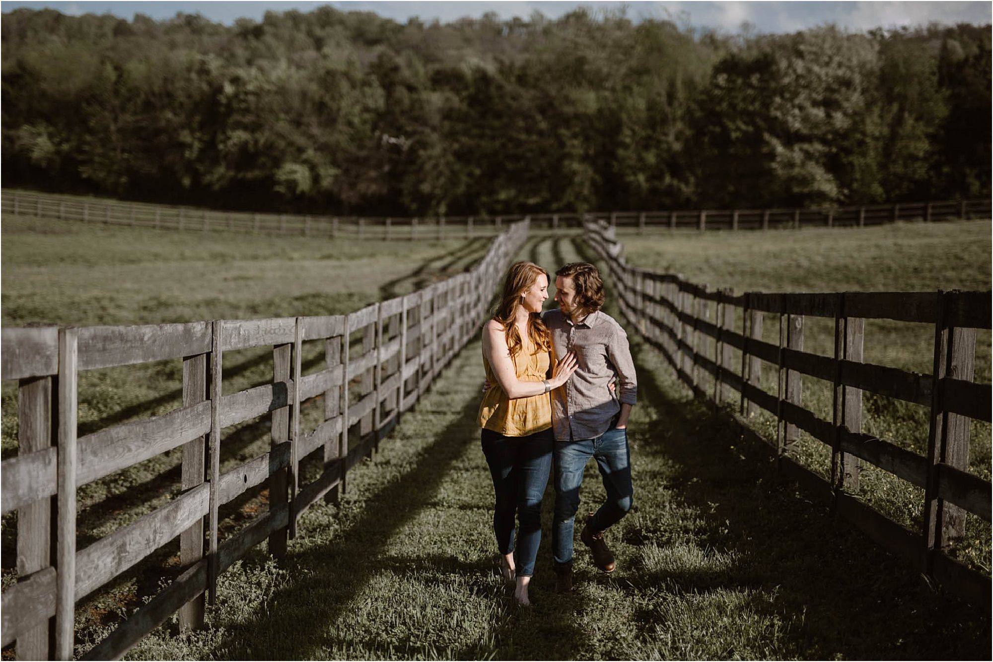 man and woman walking in field in between fences
