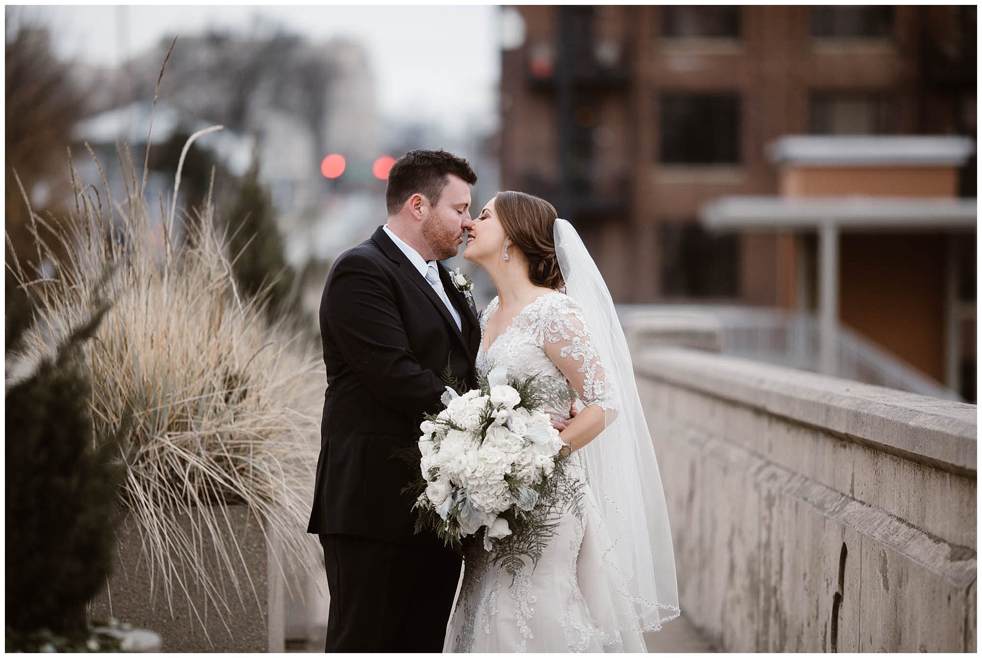 bride and groom kissing on wedding day on bridge in Knoxville