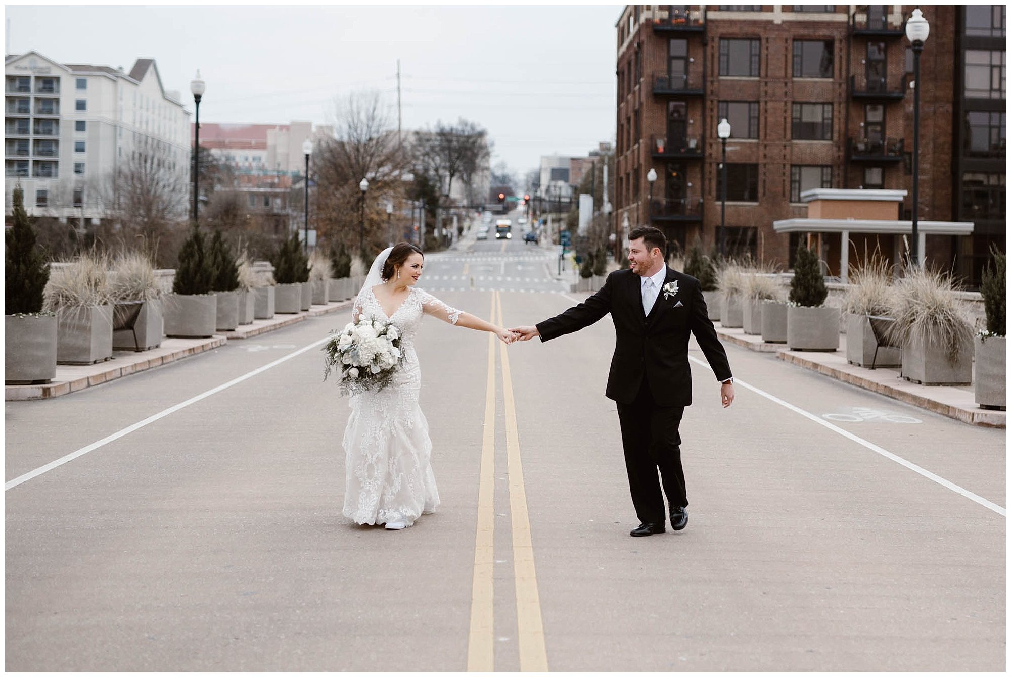 bride and groom holding hands while walking on street