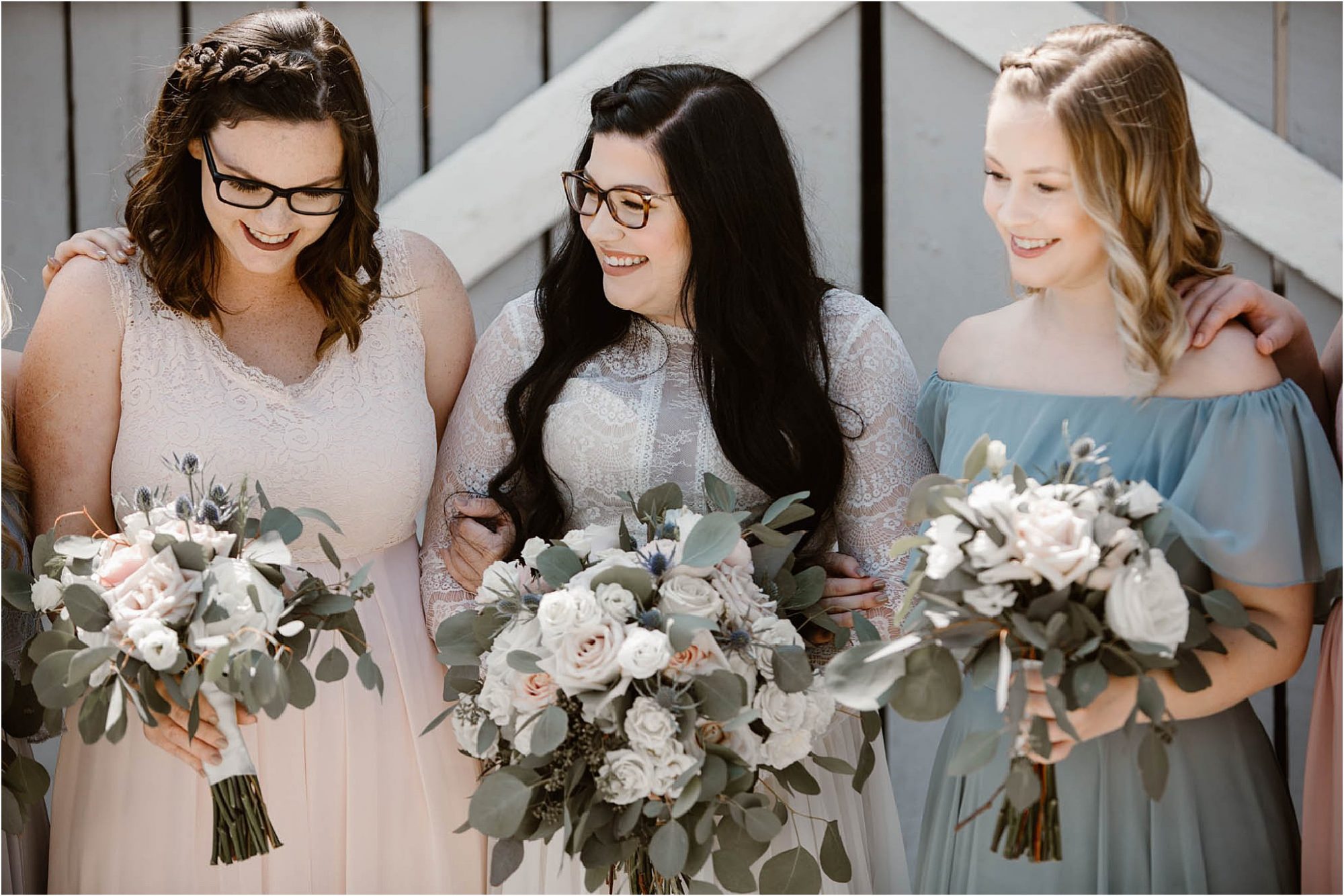 bride laughing with bridemaids in front of grey barn doors