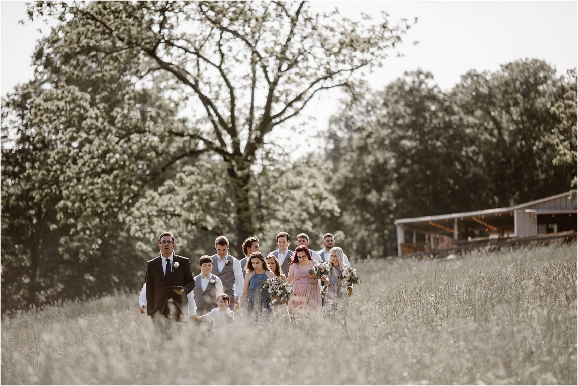 bridal party walking through field 