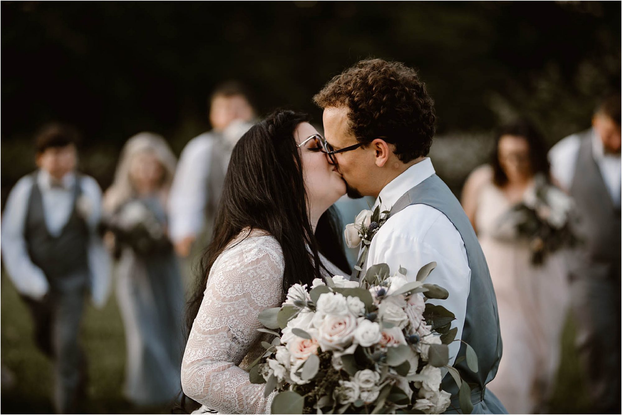 bride and groom kissing with bridesmaids and groomsmen in background