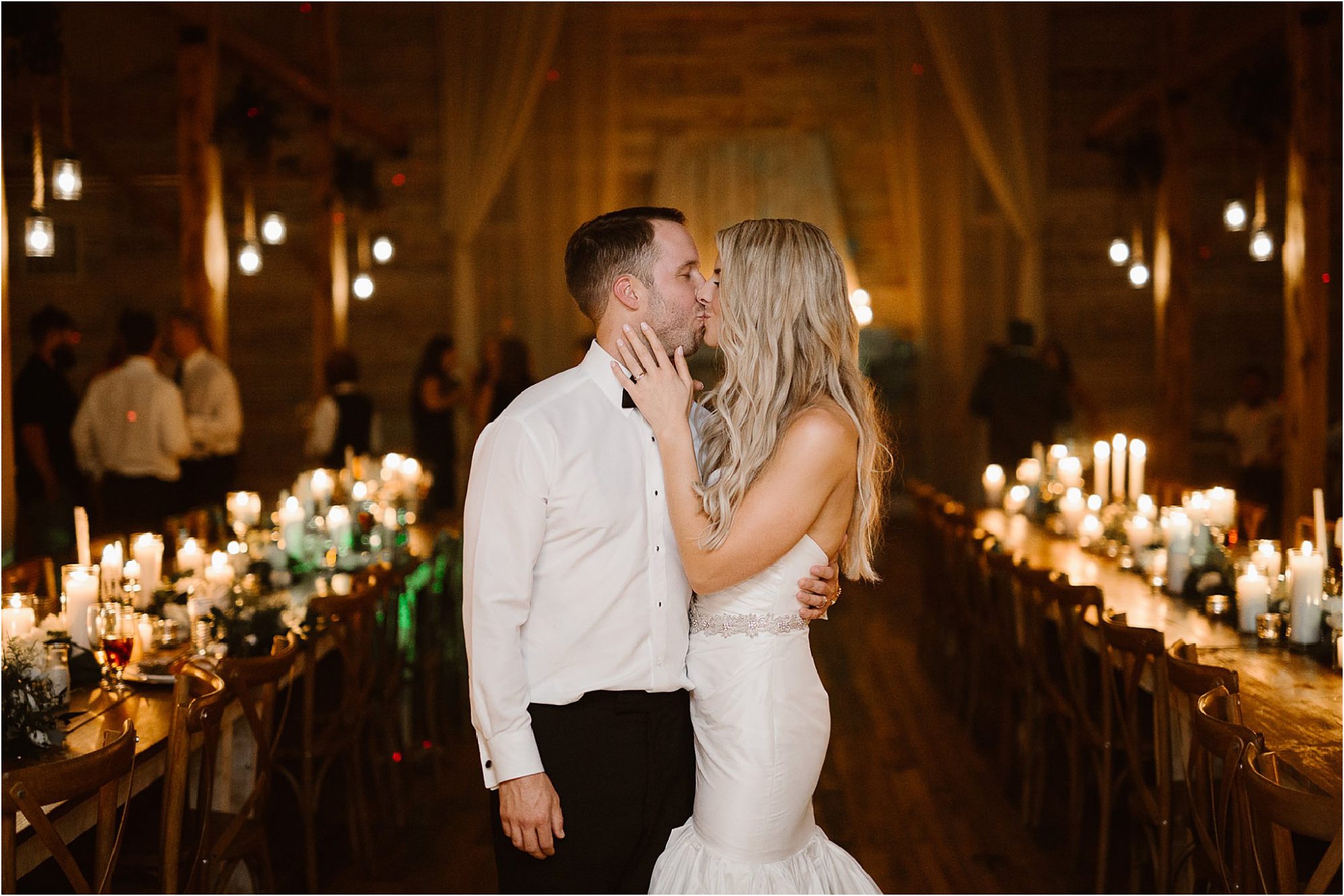 bride and groom kissing in candle lit reception