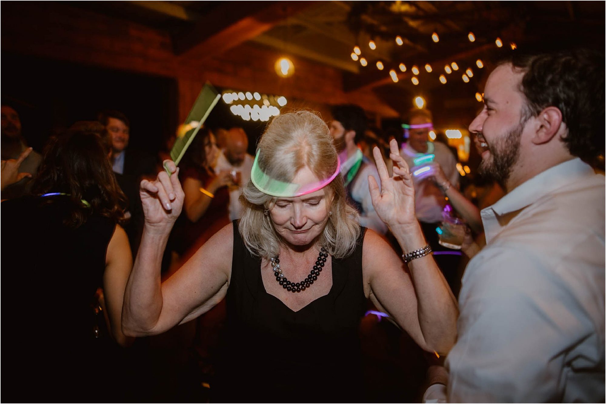 reception photo of woman dancing with glow stick on head