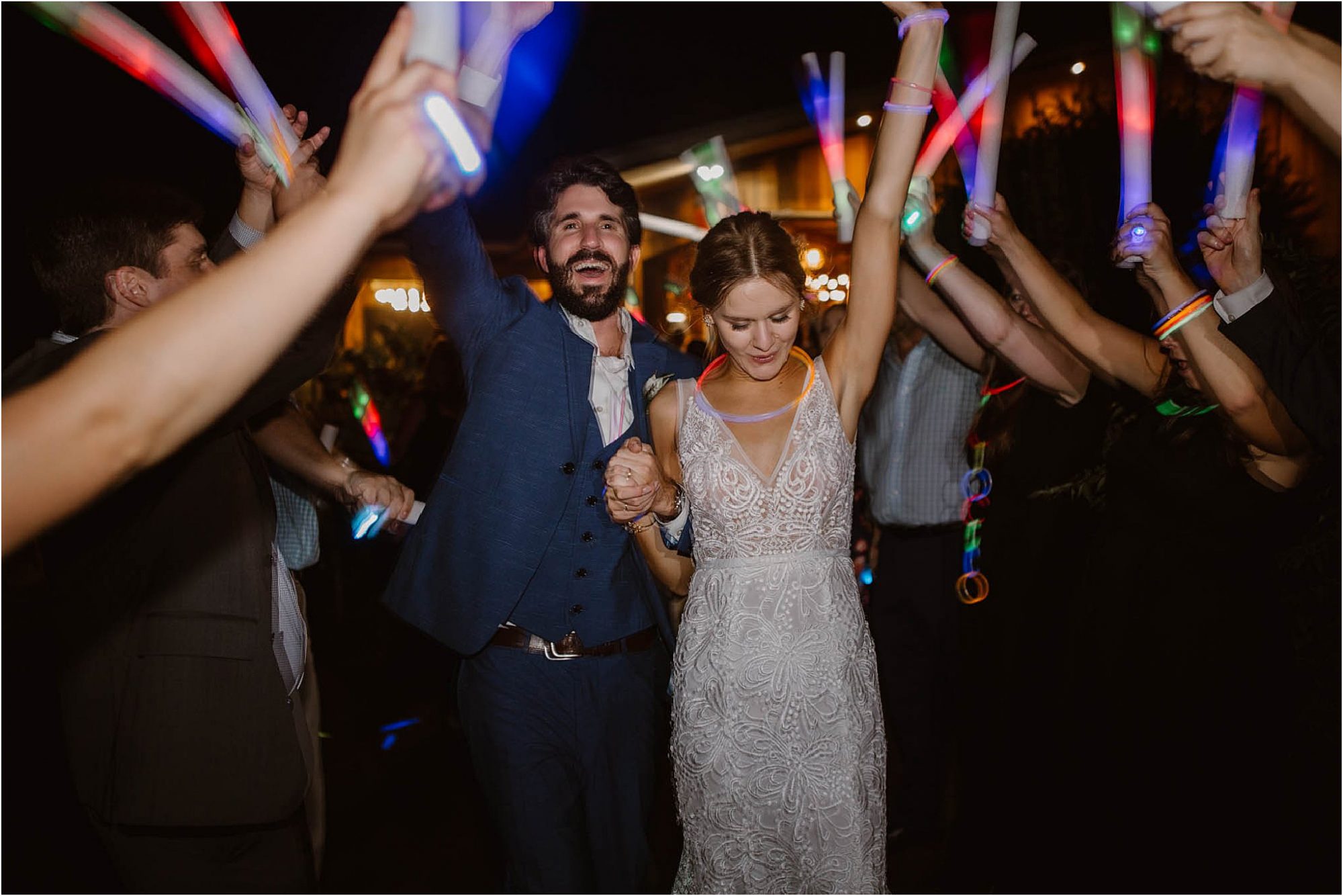 bride and groom leaving wedding with glow sticks