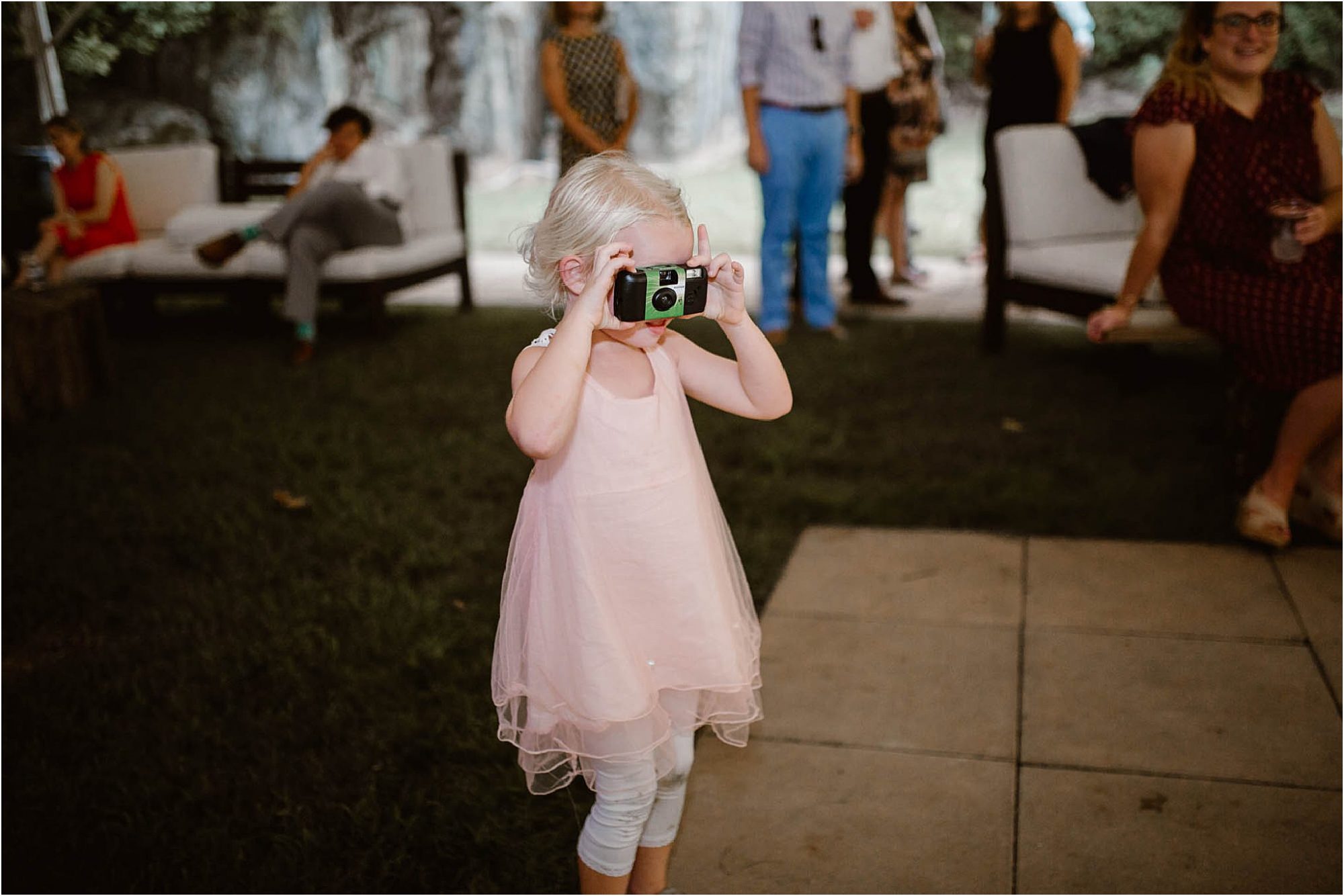 little girl holding disposable camera at wedding reception
