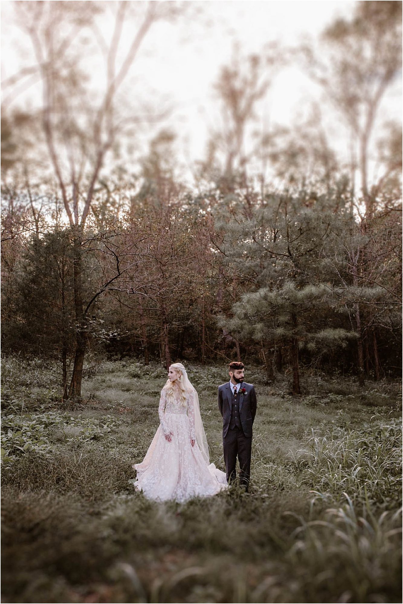 bride and groom standing in a field at sunset