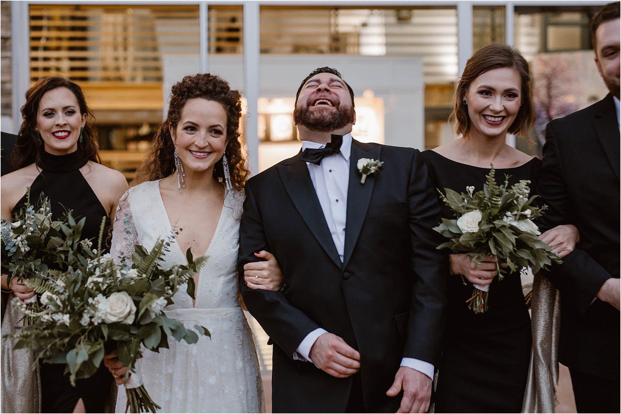 groom laughing while standing with the bridal party