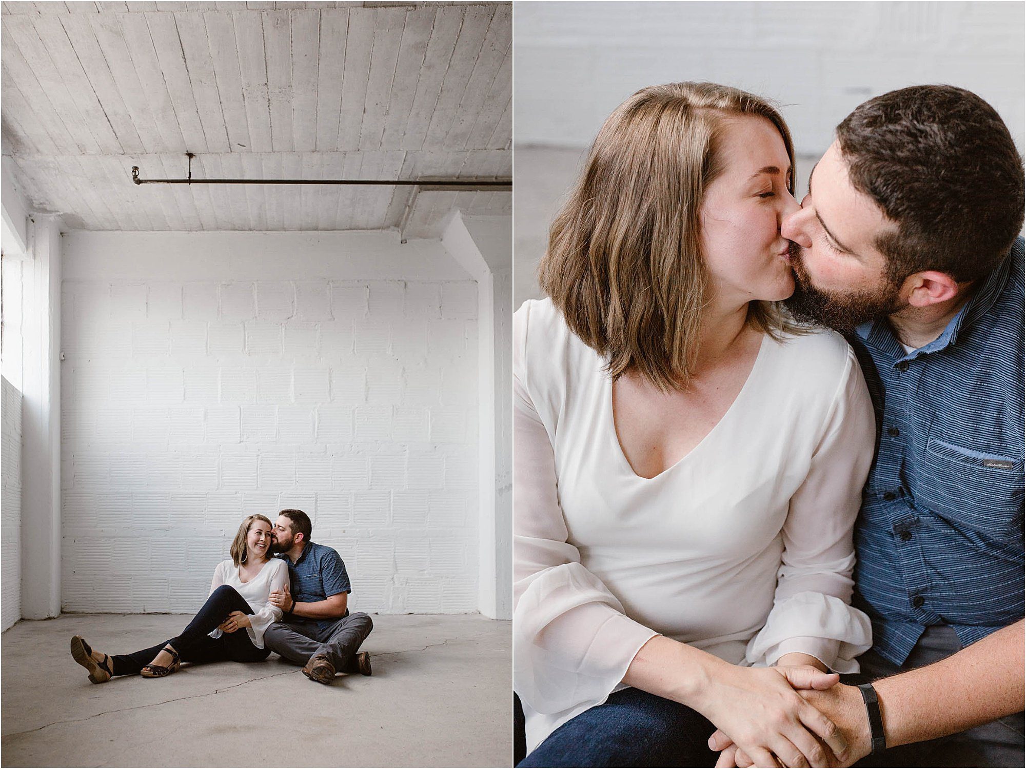 man and woman sitting and kissing against white warehouse wall