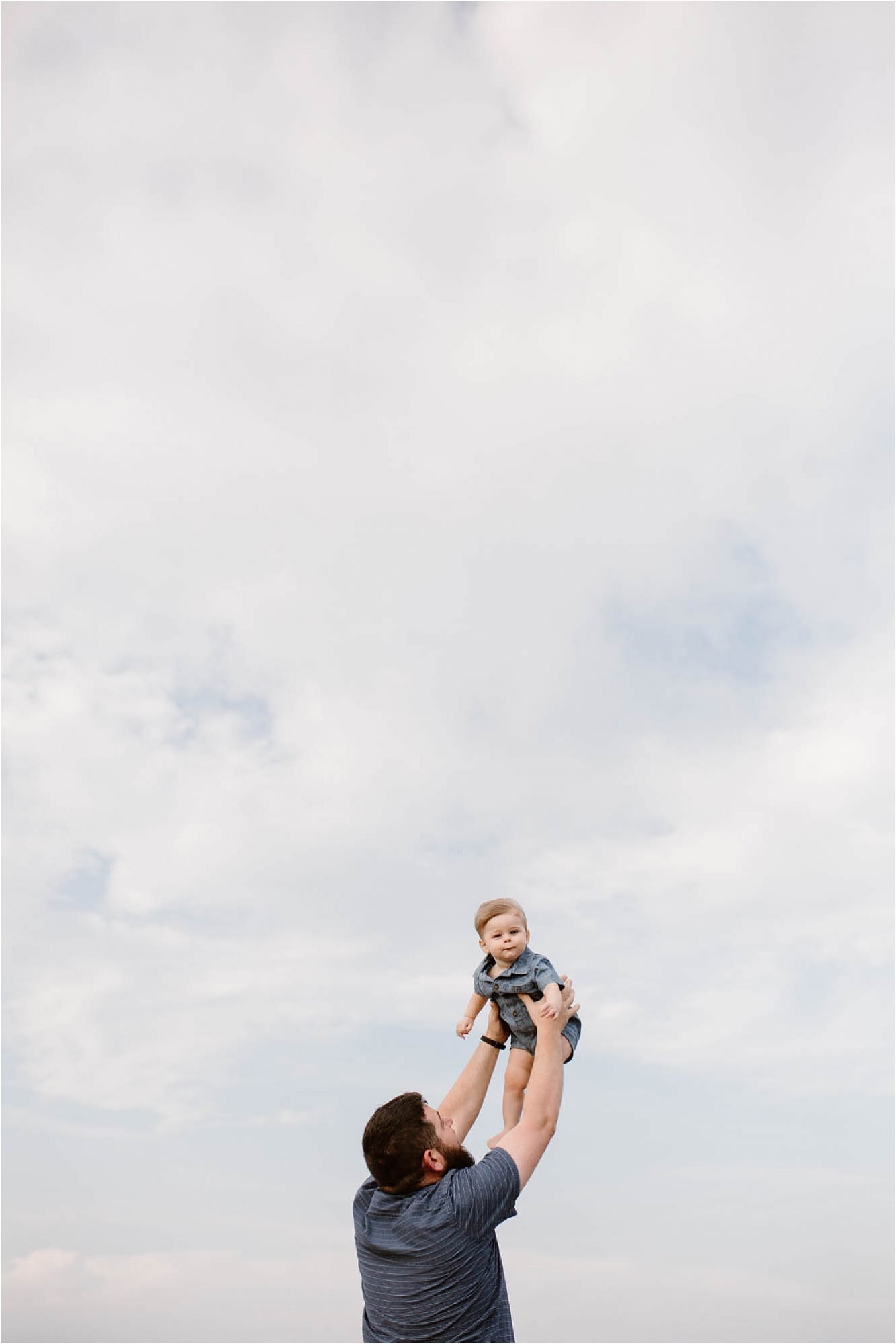 man lifting baby up into sky
