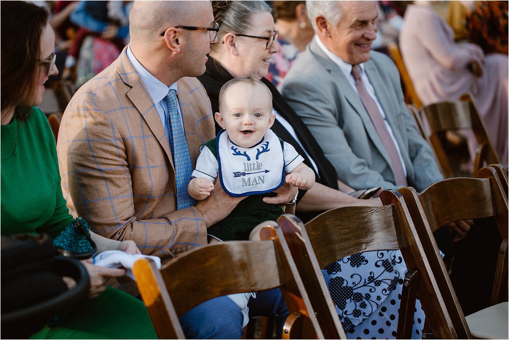 baby sitting on adult's lap at wedding ceremony