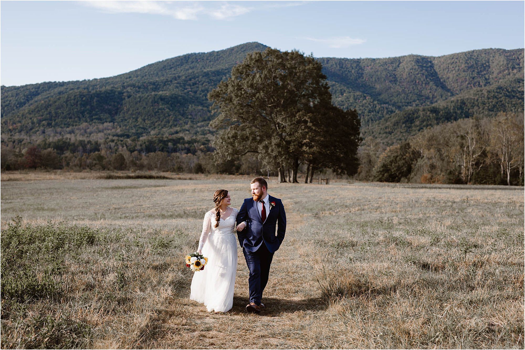 bride and groom walk along path in open field