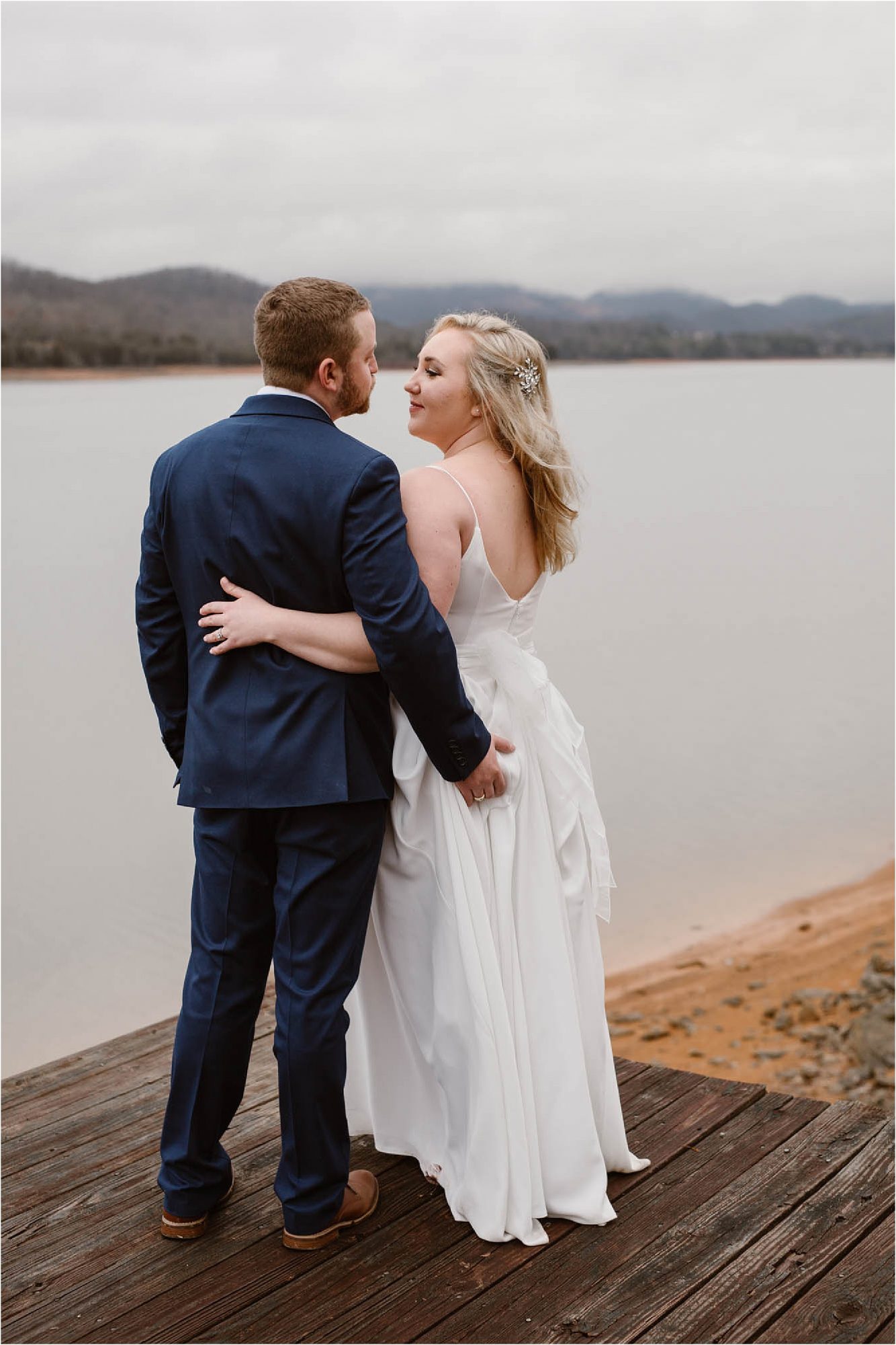 bride and groom hugging while standing on dock