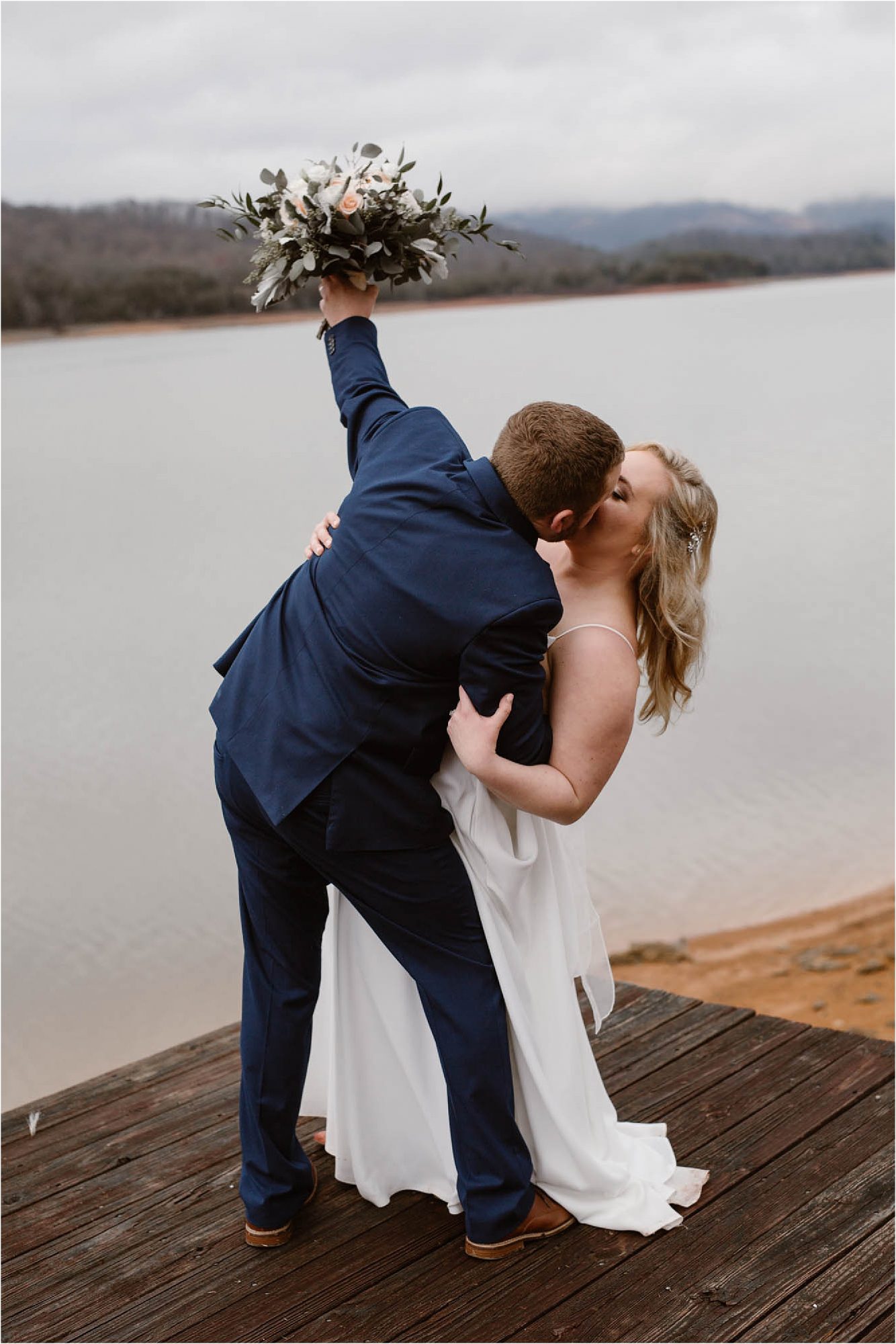 groom kissing bride while holding bouquet