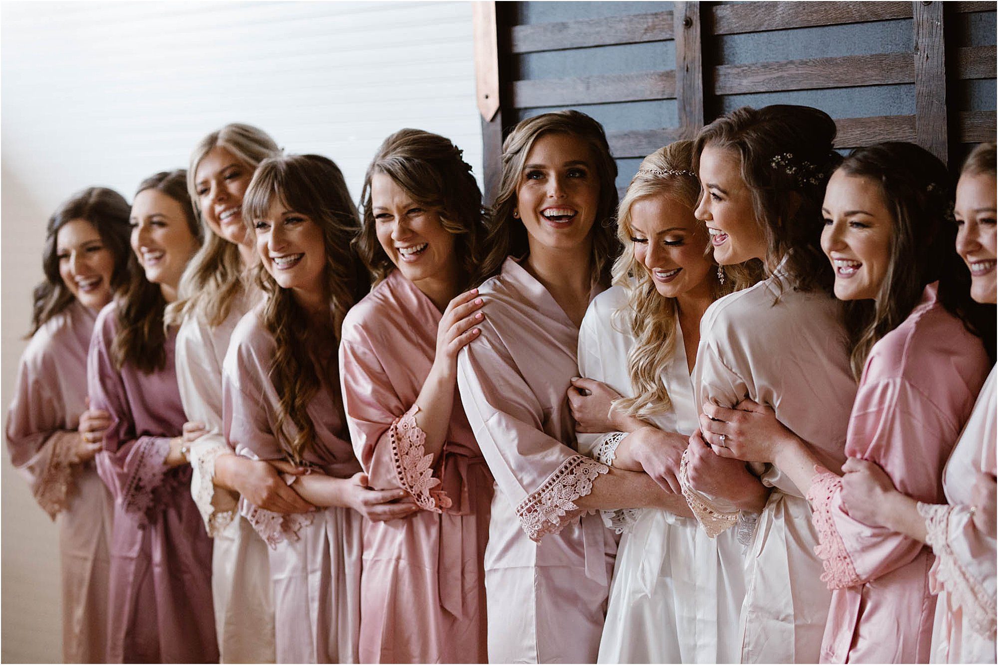 bridesmaids and bride hugging in pink and white robes