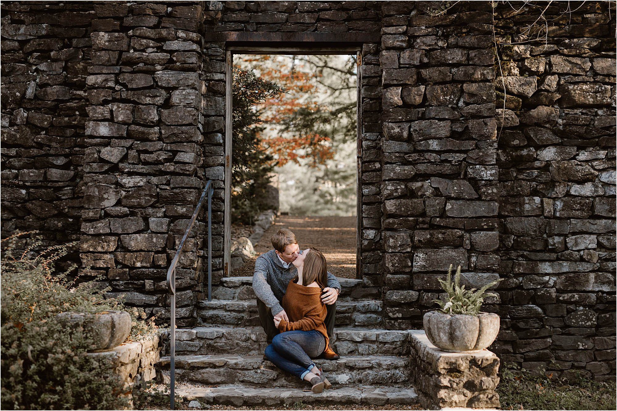 man and woman sitting on stone steps at engagement session