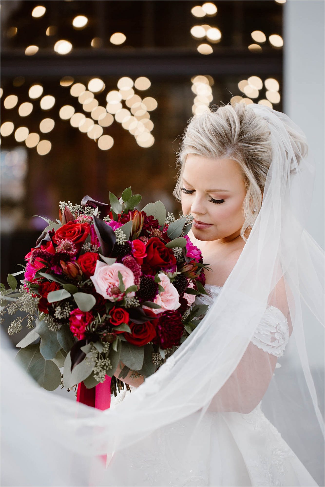 bride holding red and burgundy wedding bouquet