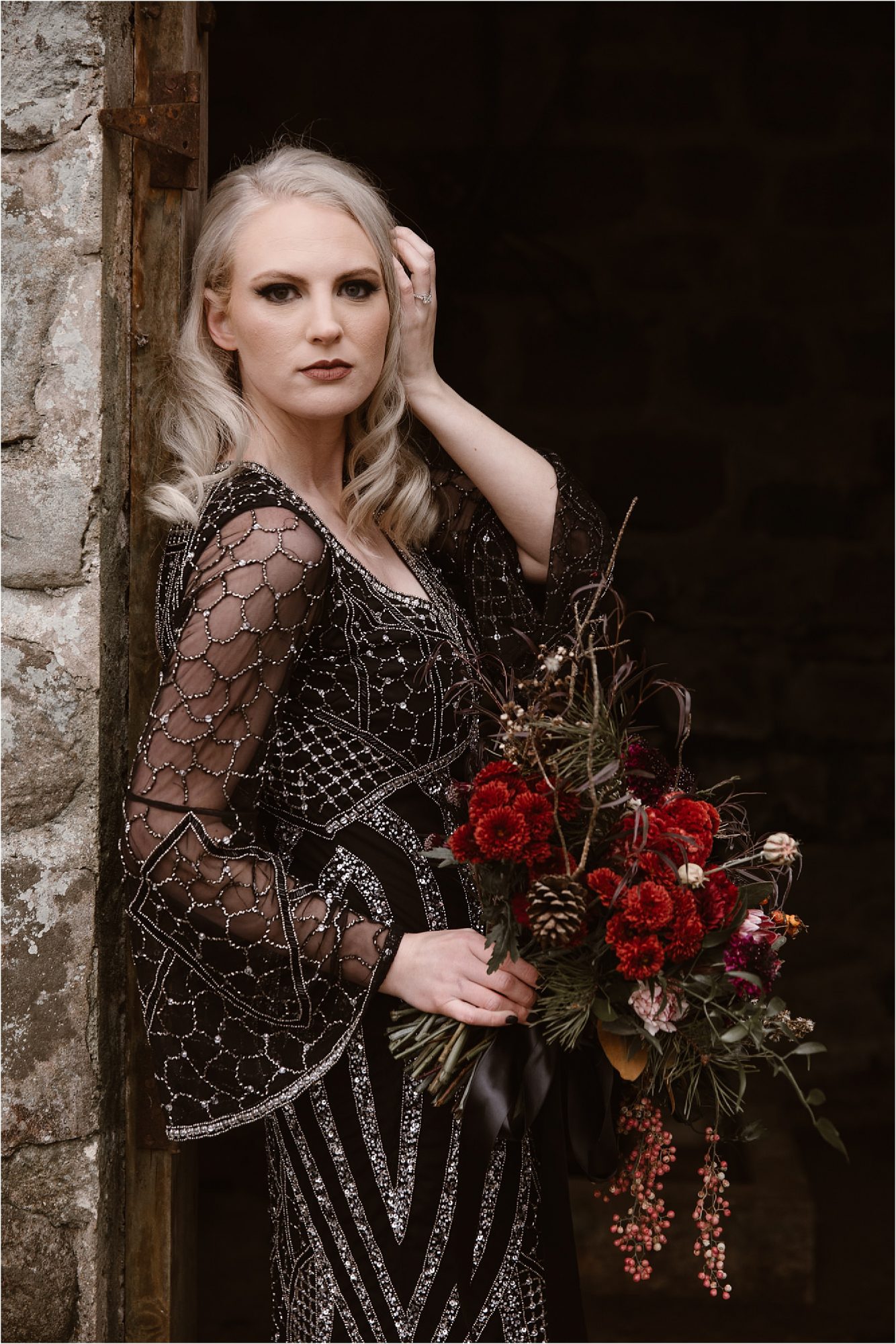 bride in beaded black dress with red bouquet