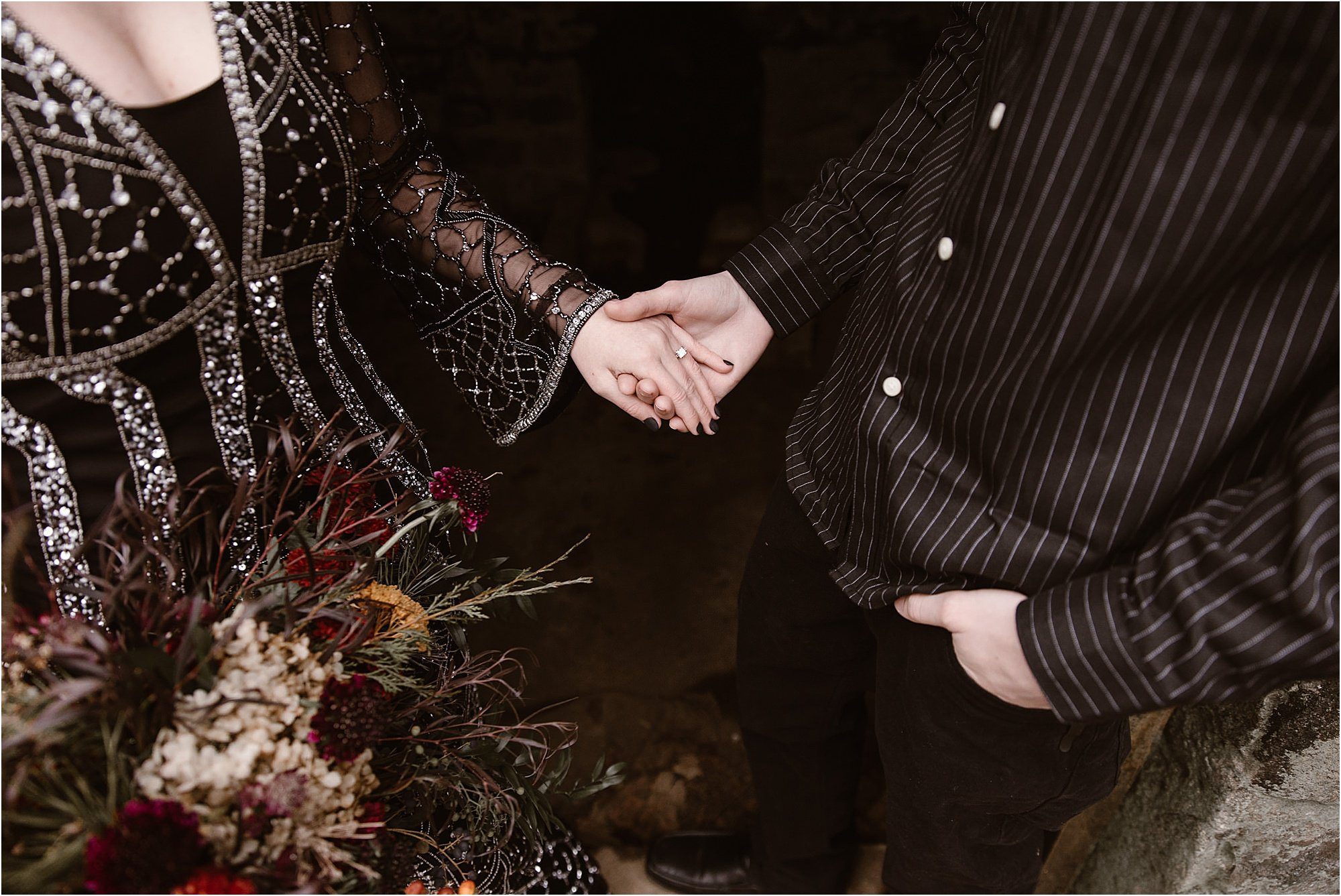 man and woman holding hands while wearing black wedding outfits