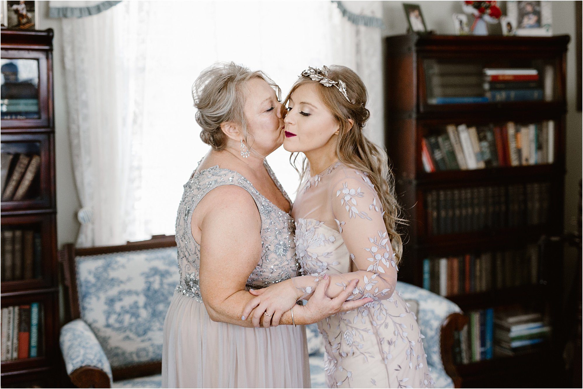 bride and mother kissing on cheek on wedding day