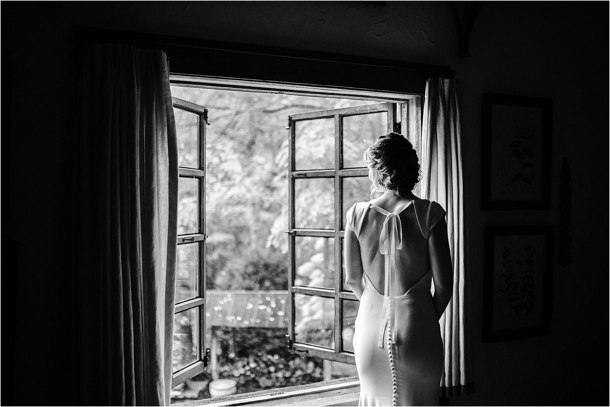 black and white photo of bride peering out of window