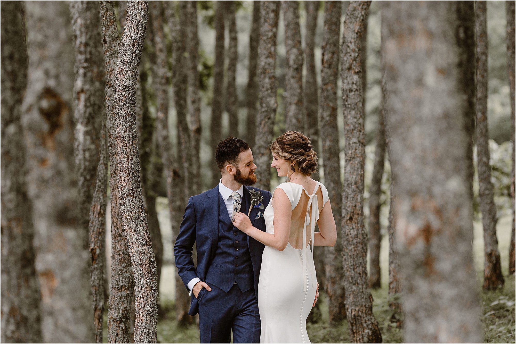 bride and groom stand In forest