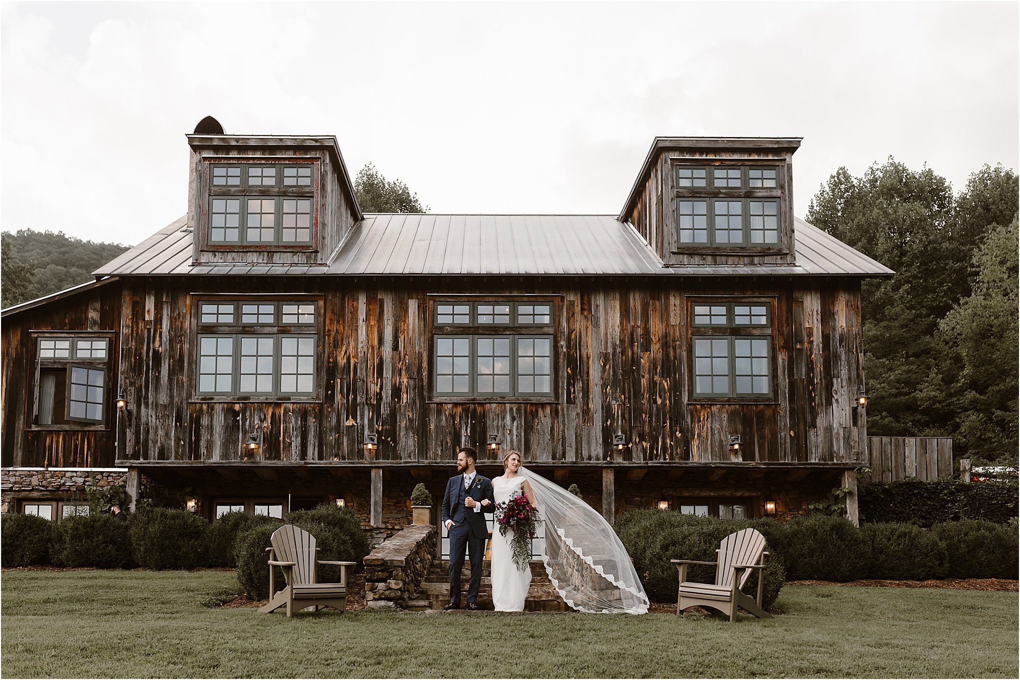 bride and groom stand in front of lodge at The Vineyards at Betty's Creek