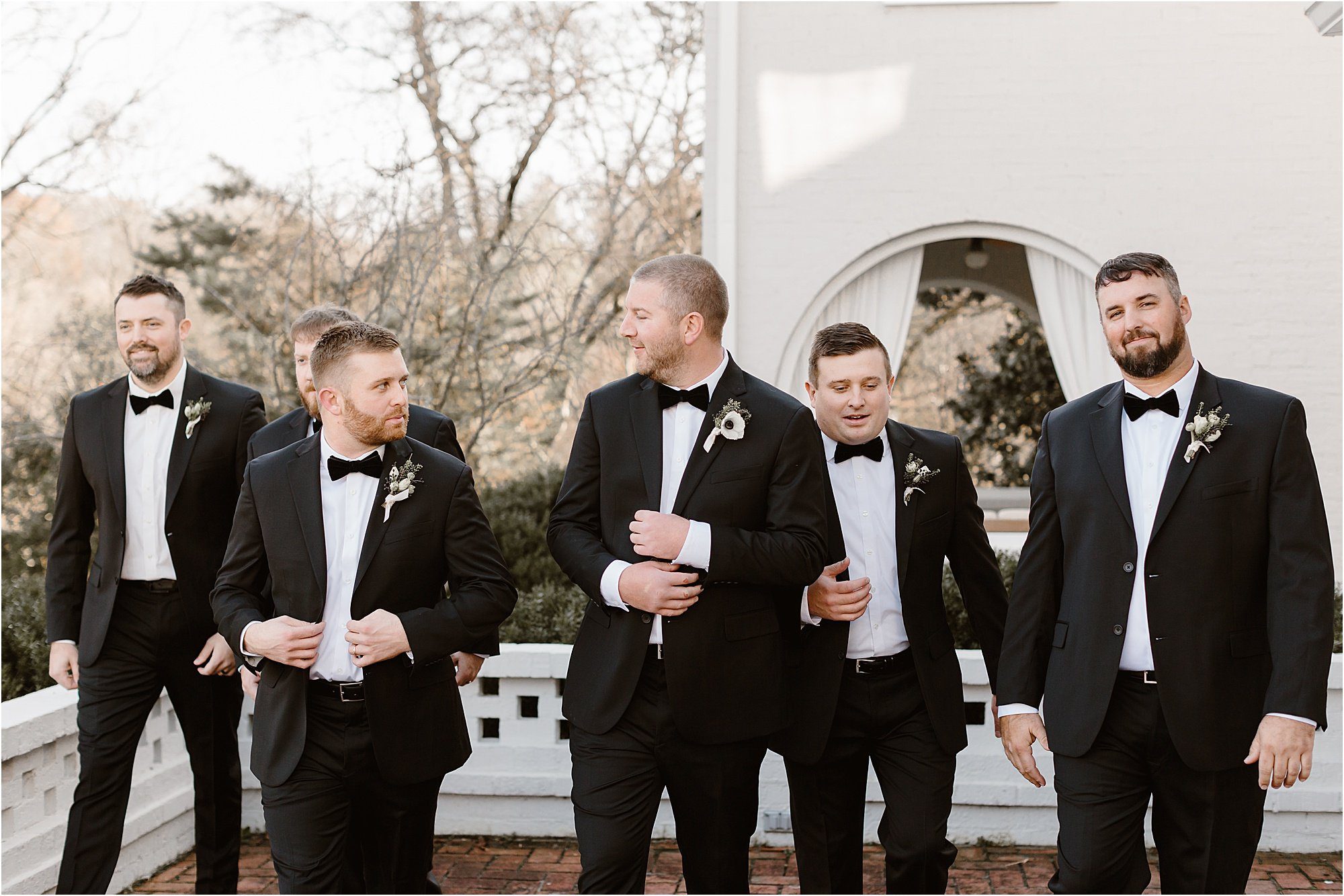 groom and groomsmen in black-tie suits
