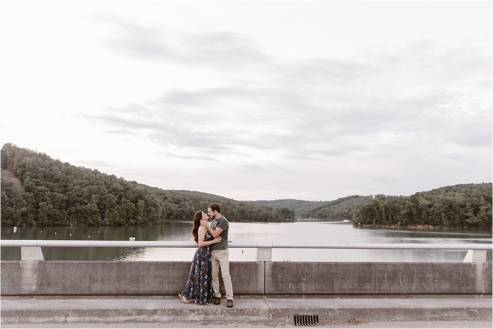 man and woman kiss over bridge