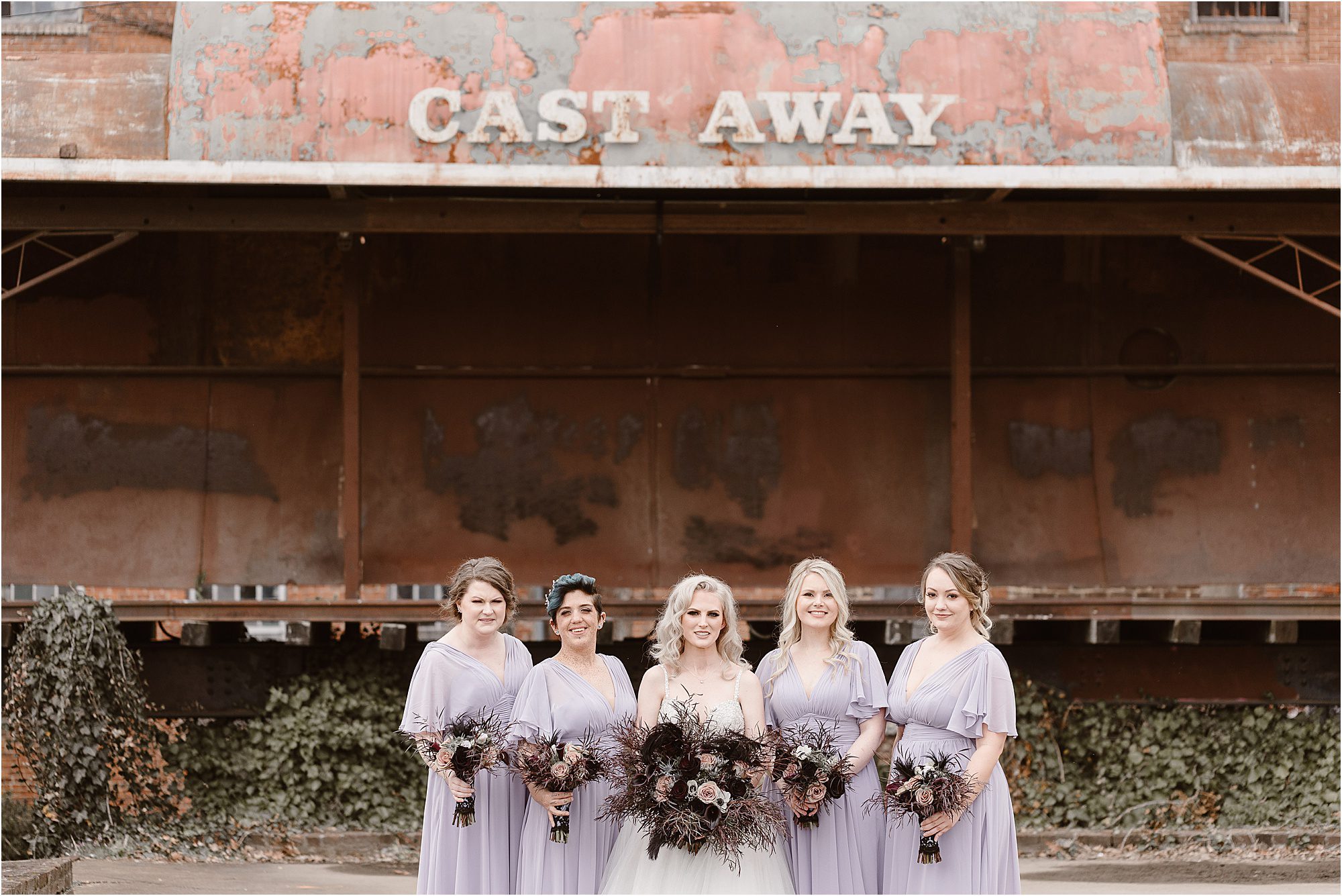 bride and bridesmaids with black bouquet with purple bridesmaid dresses
