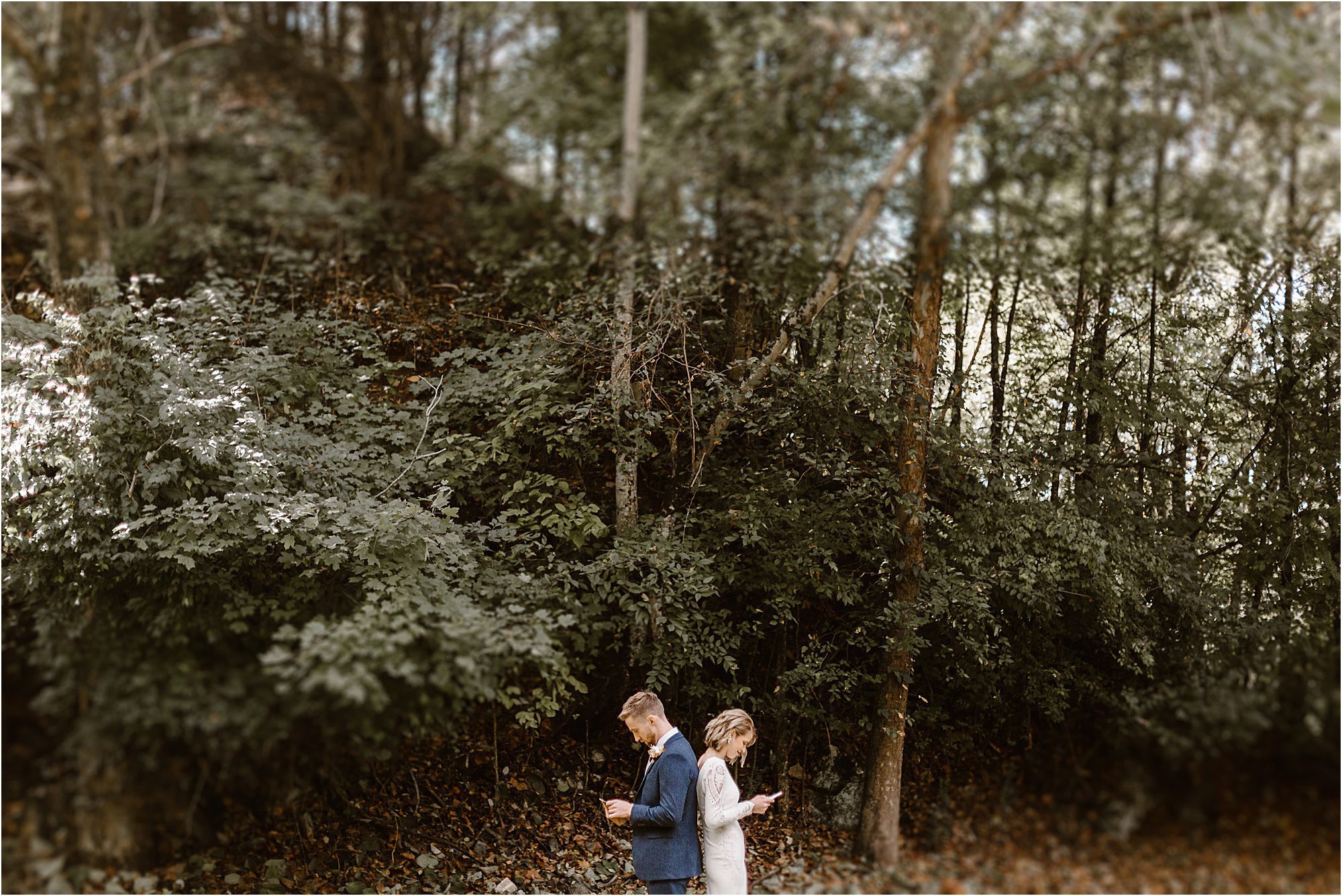 bride and groom standing back to back reading personal wedding vows in forest