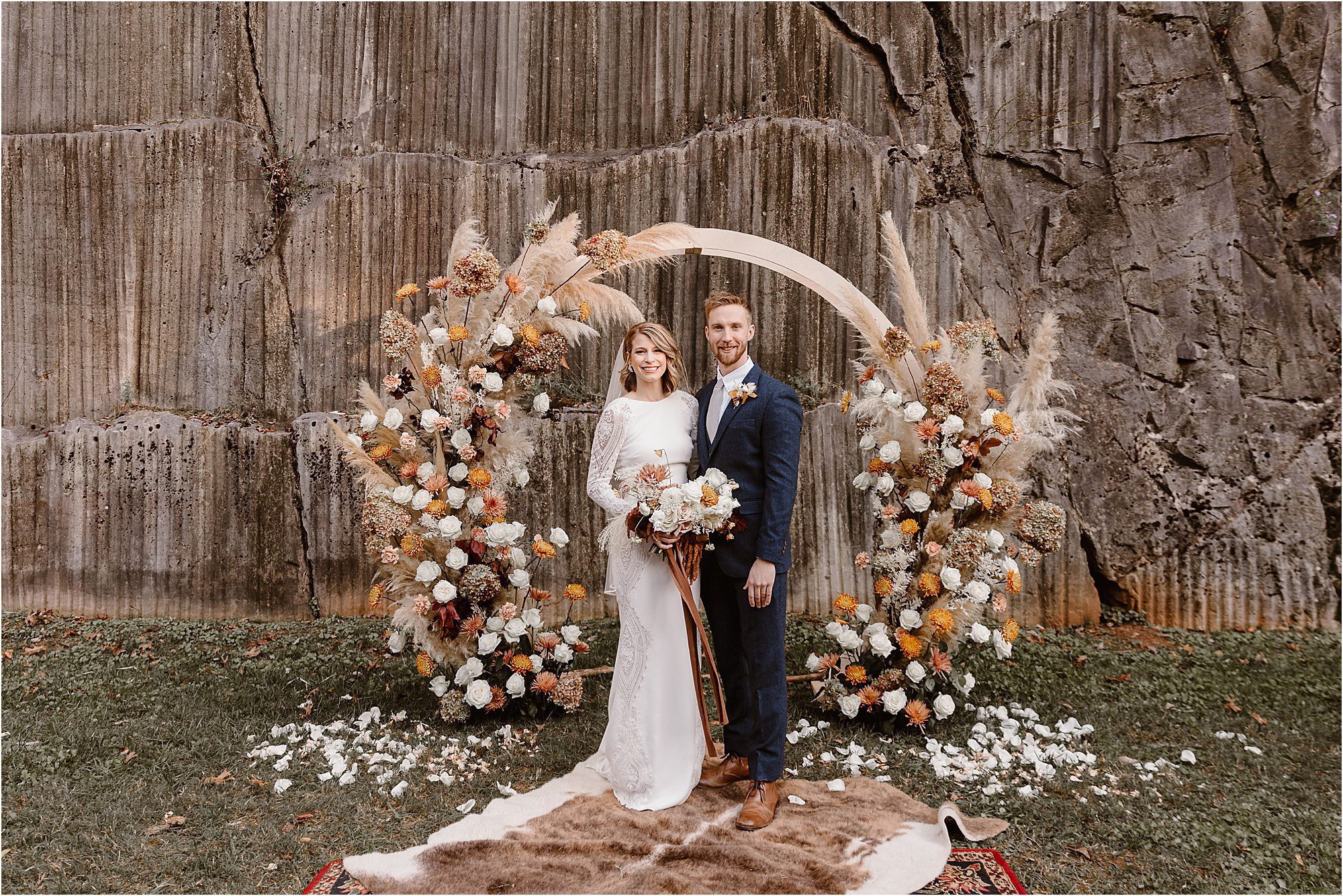 bride and groom stand in front of boho circle ceremony arbor at autumnal wedding
