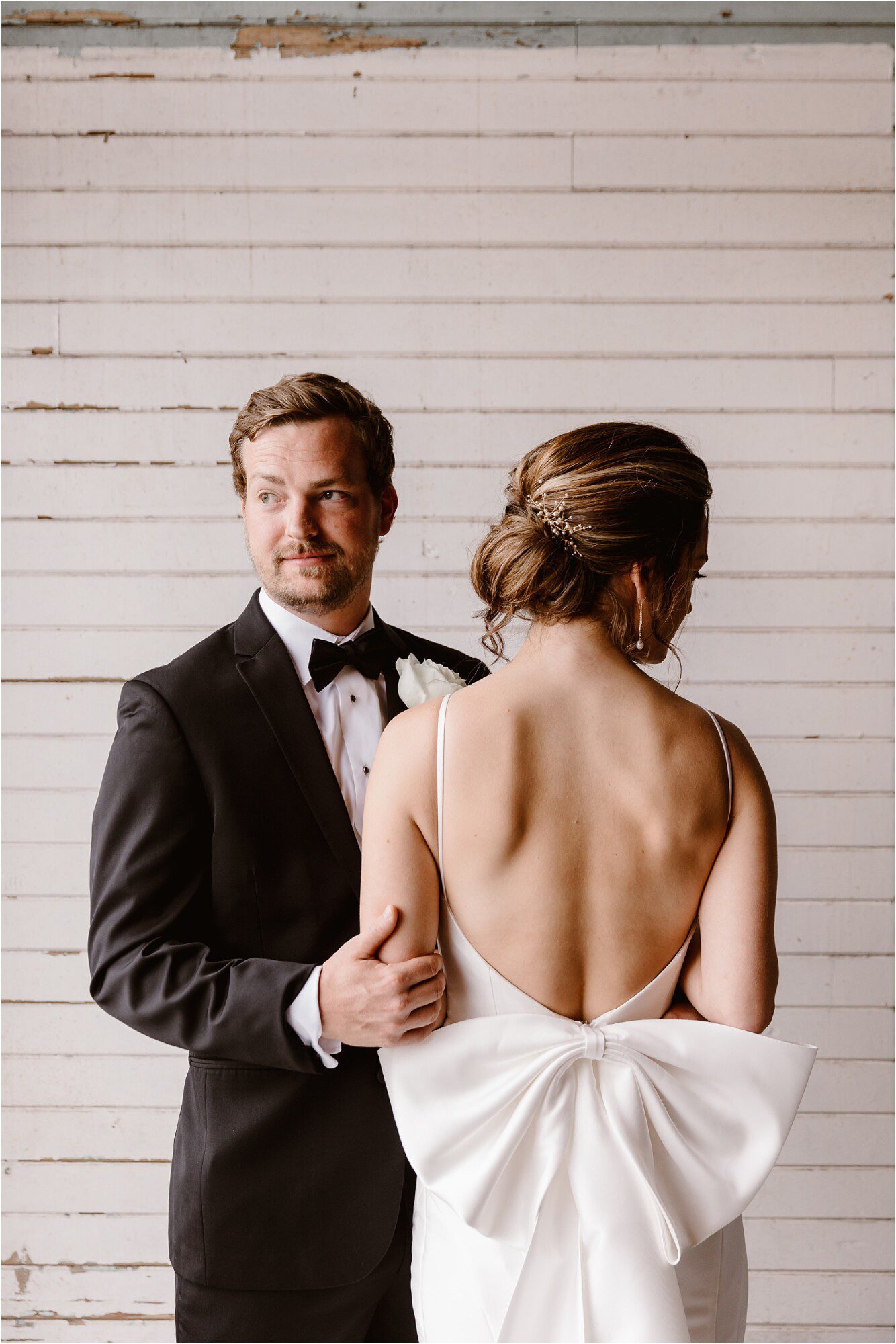 wedding couple photo of groom and bride with big bow on back of wedding dress