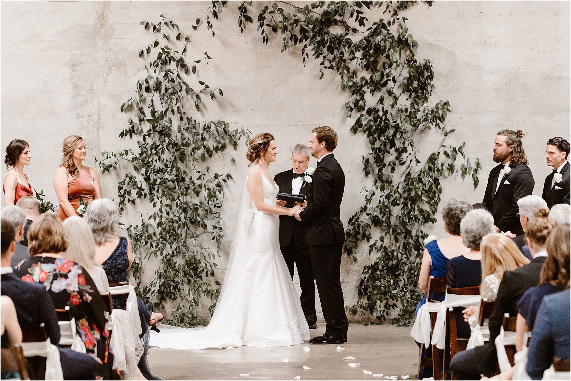 wedding ceremony infront of greenery arbor