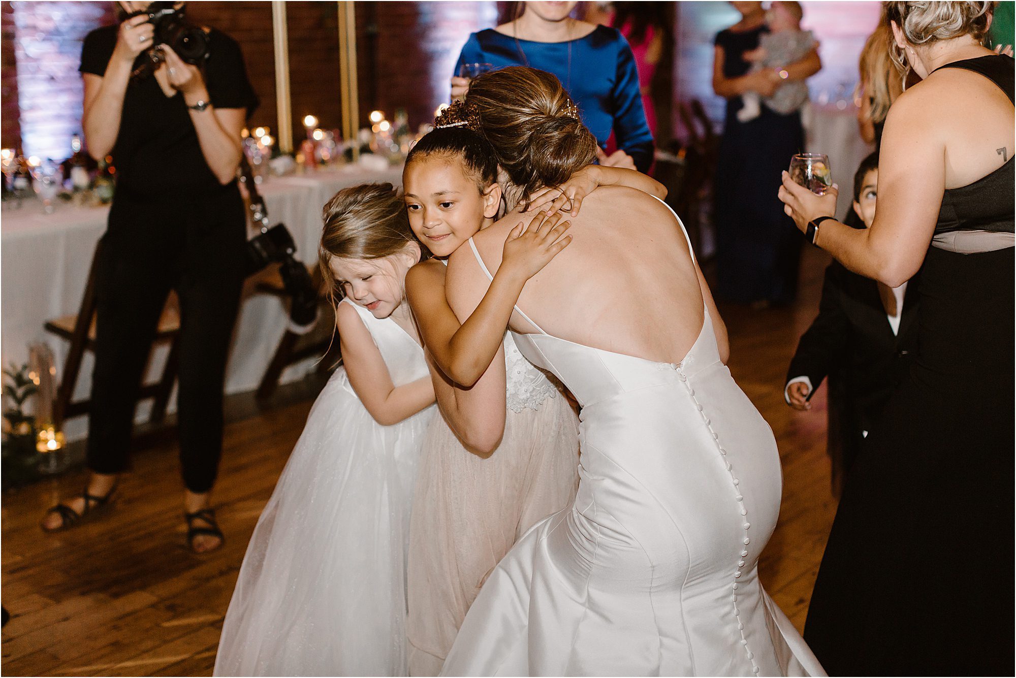 bride hugs flower girls at wedding reception
